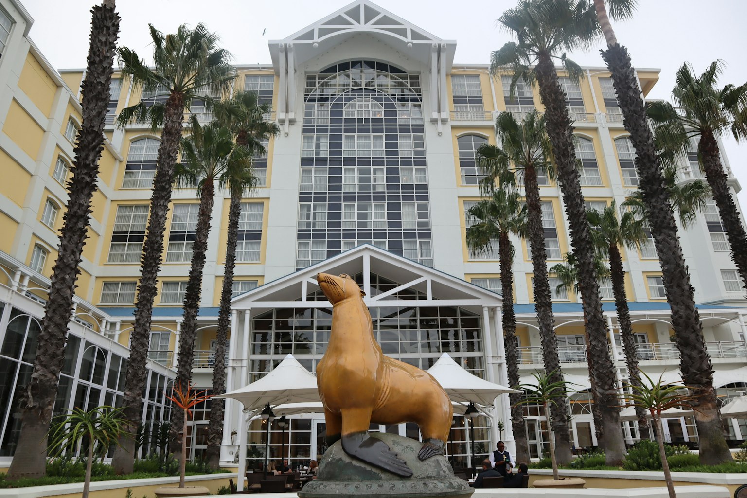 Fachada de hotel con una gran estatua de foca y palmeras
