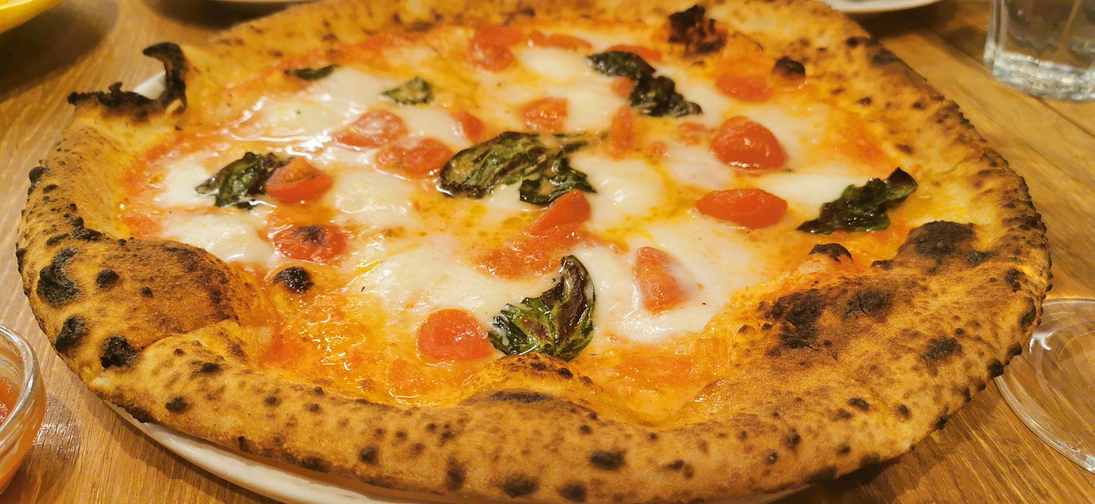 Pizza fraîchement cuite garnie de tomates et de basilic avec du fromage fondu