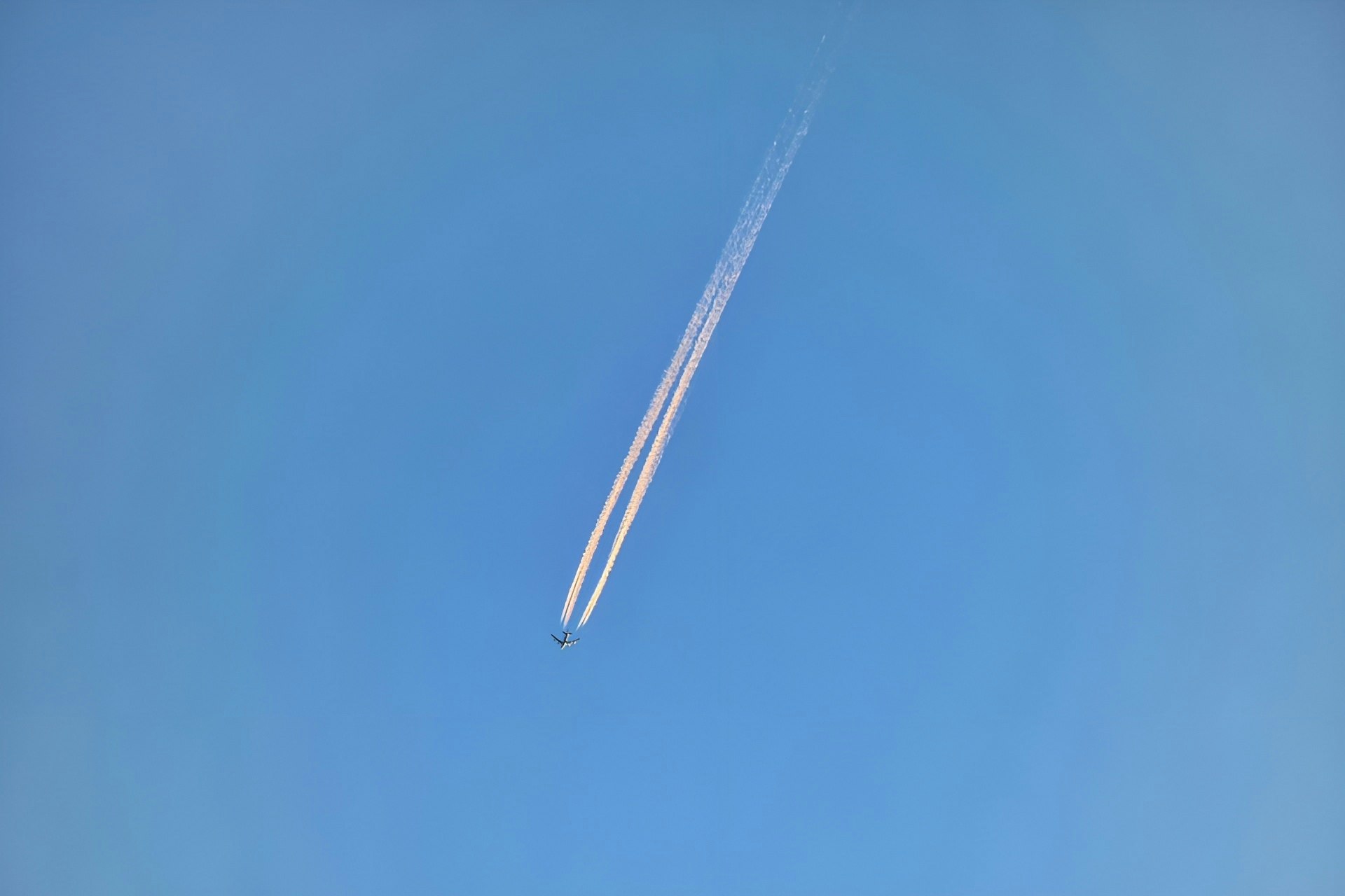 飛行機雲が伸びる青空の空