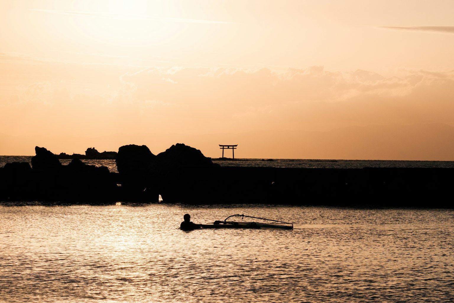 夕陽下海上漁夫的輪廓與岩石海岸
