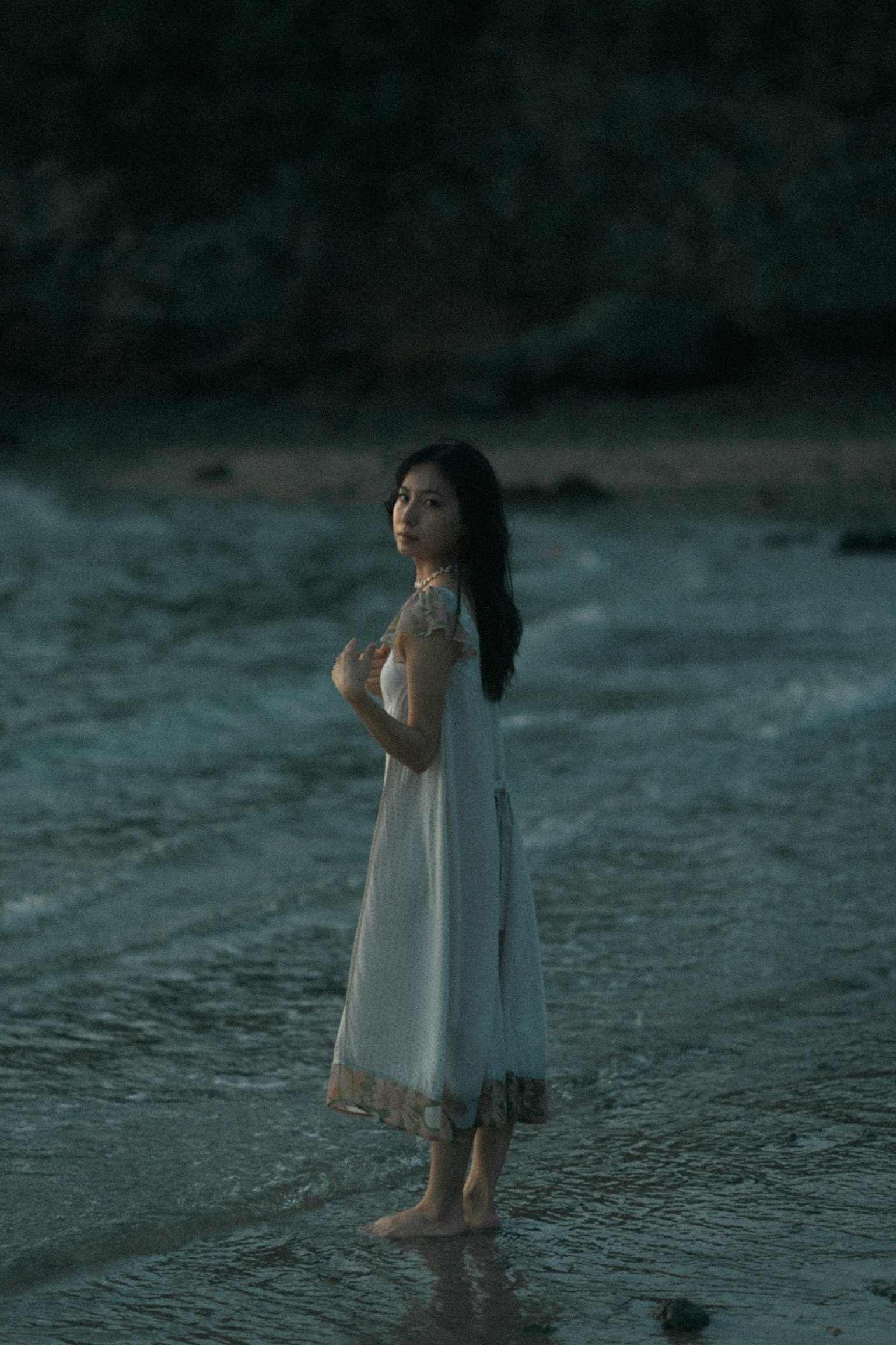 一位穿著白色裙子的女性站在海邊