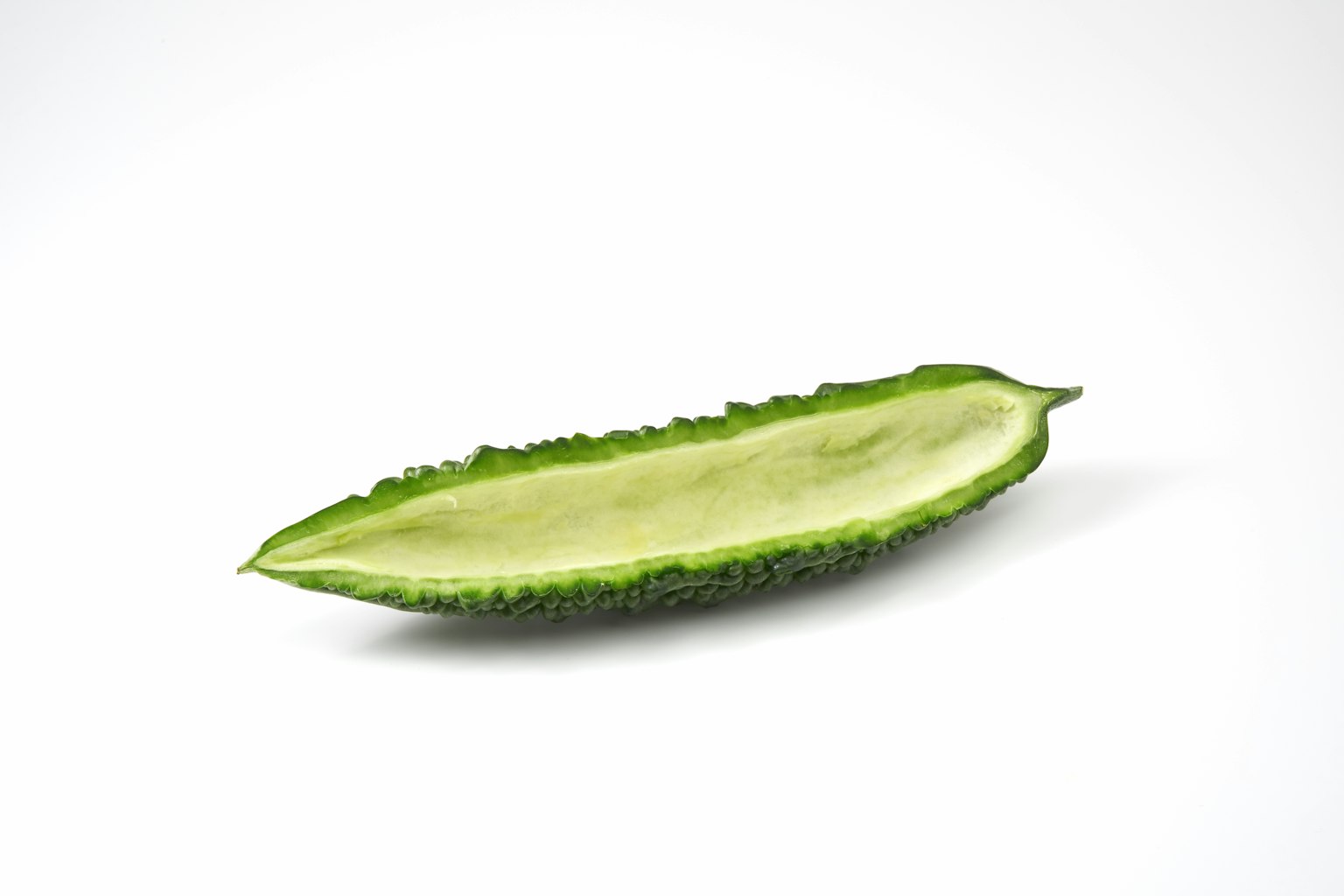 흰색 배경에 놓인 녹색 쓴 멜론의 단면