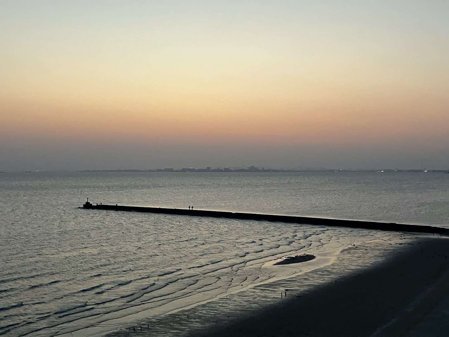 Garis pantai tenang saat matahari terbenam dengan air tenang