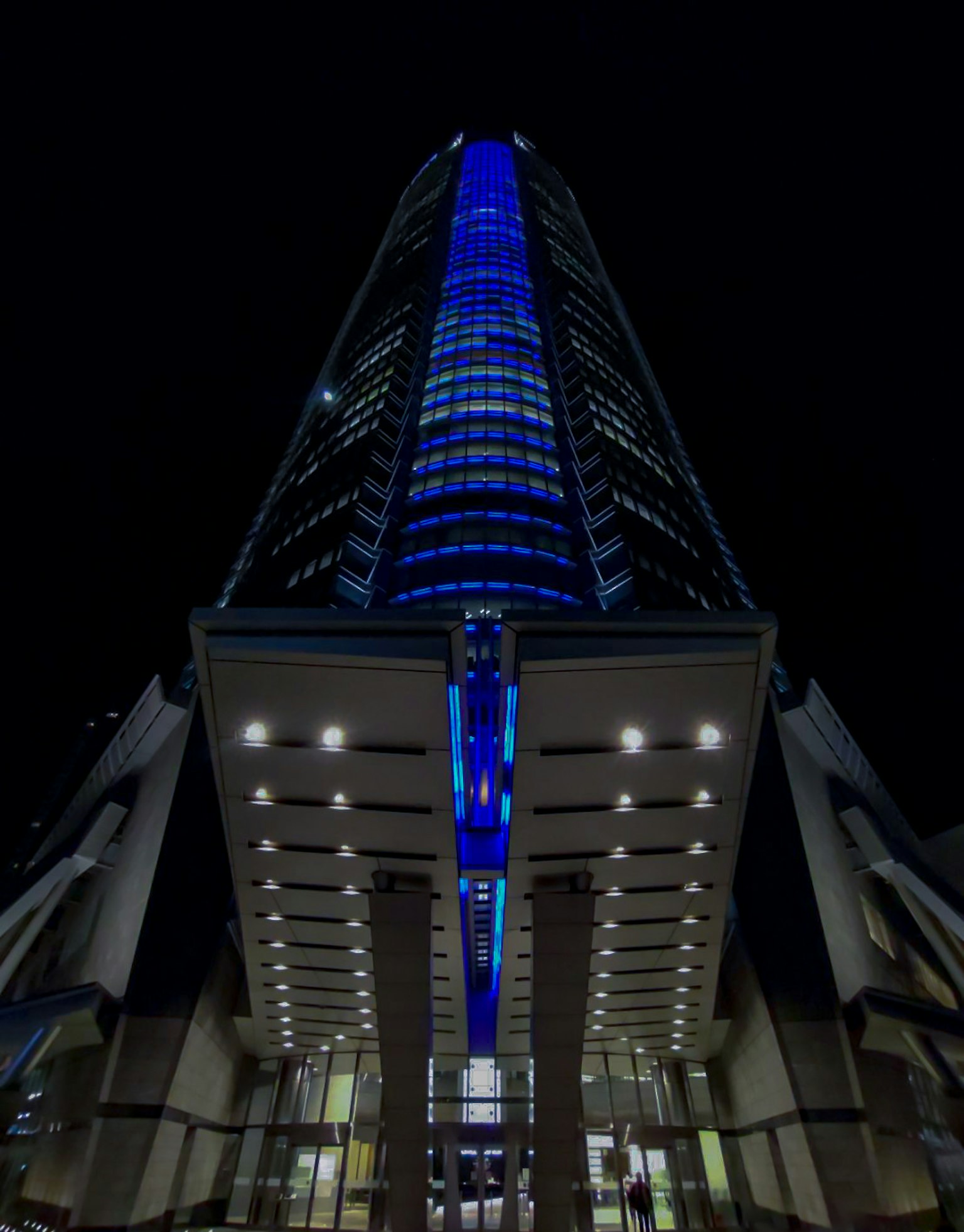 从下面看夜间用蓝色灯光照亮的高楼