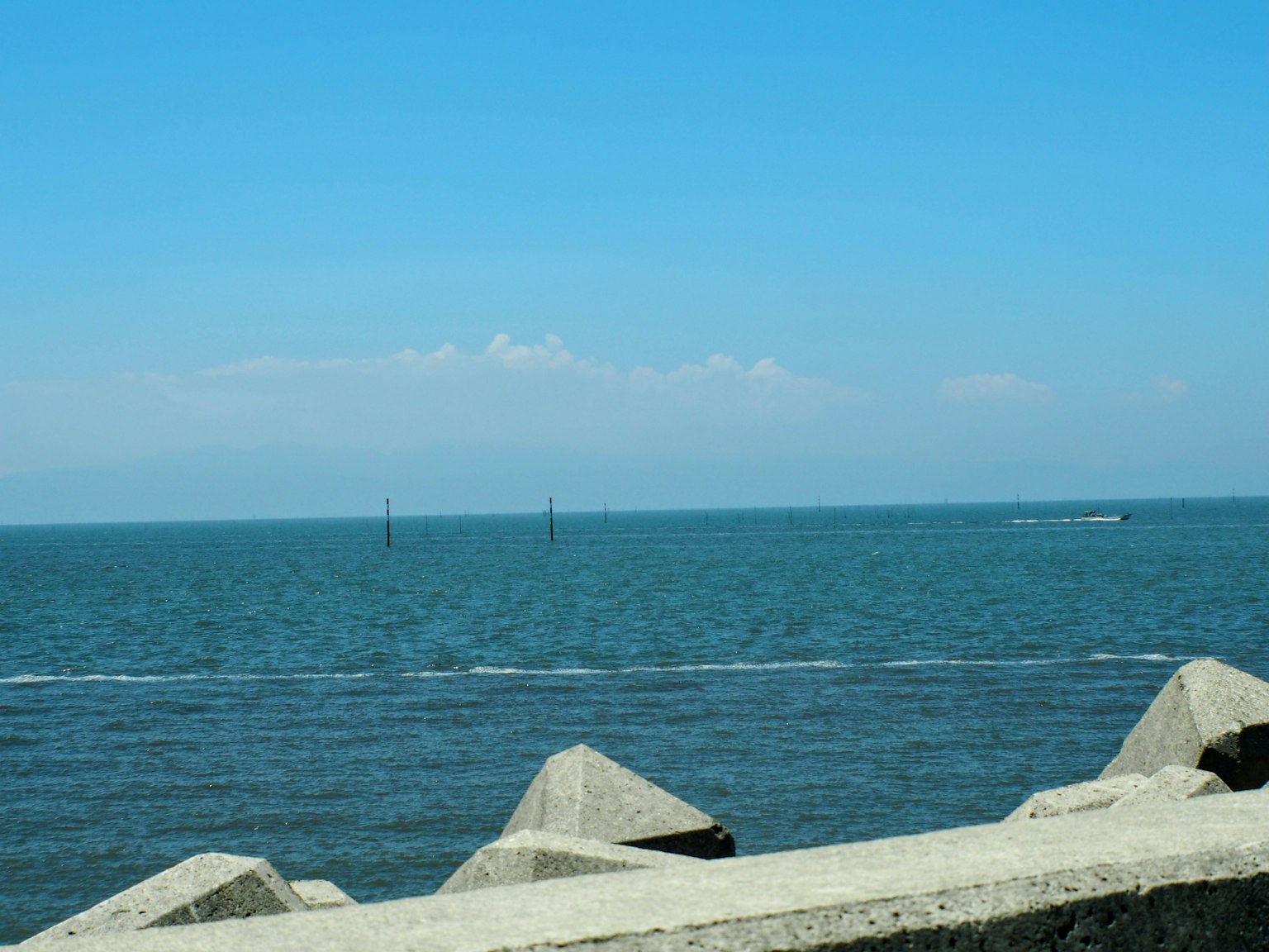 Mare blu con nuvole bianche sullo sfondo strutture rocciose lungo la costa