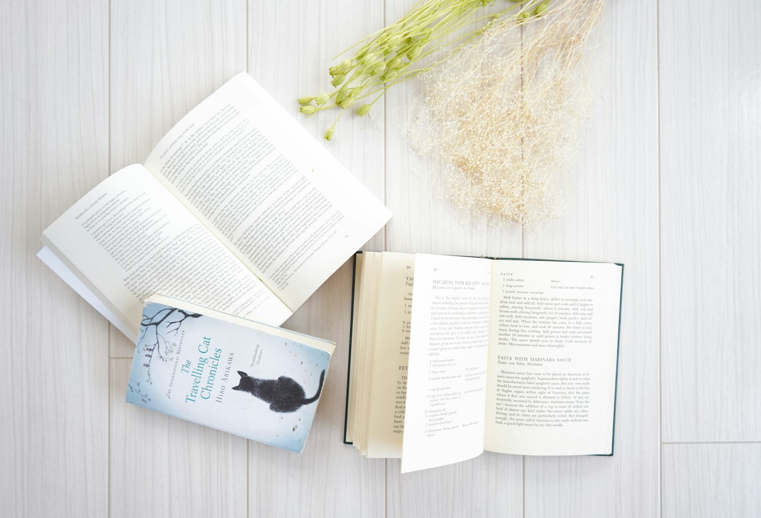 A scene with open books and floral arrangement on a white floor