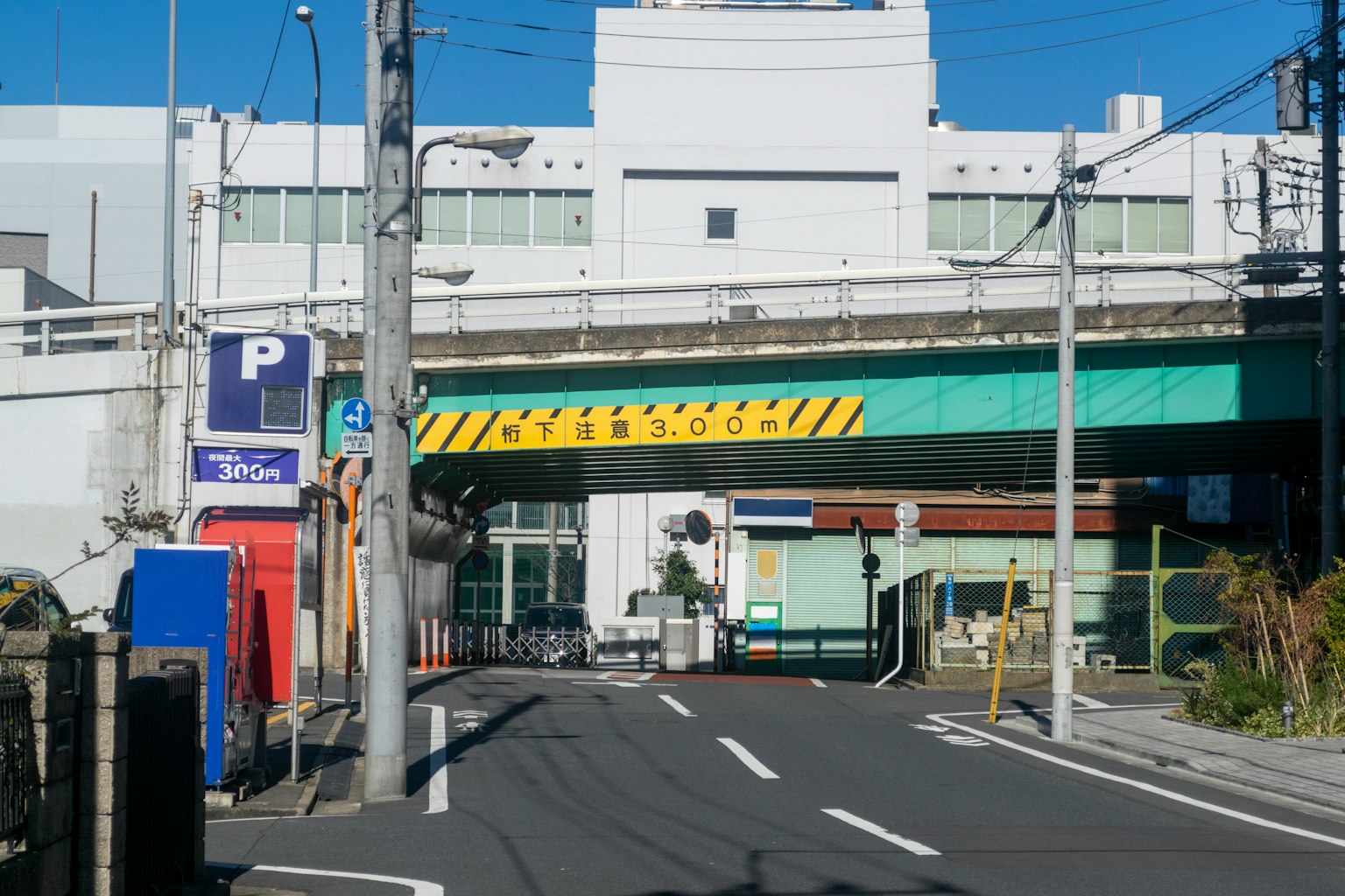 Vista de calle con una carretera bajo un puente elevado y un letrero de estacionamiento visible
