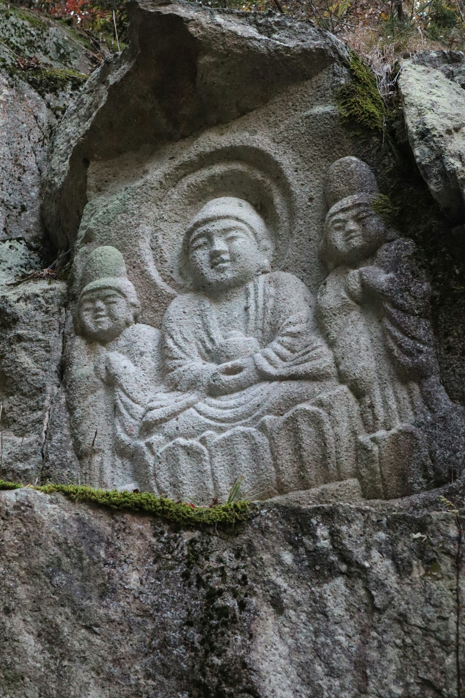 Carved Buddha statue with two bodhisattvas on a rock