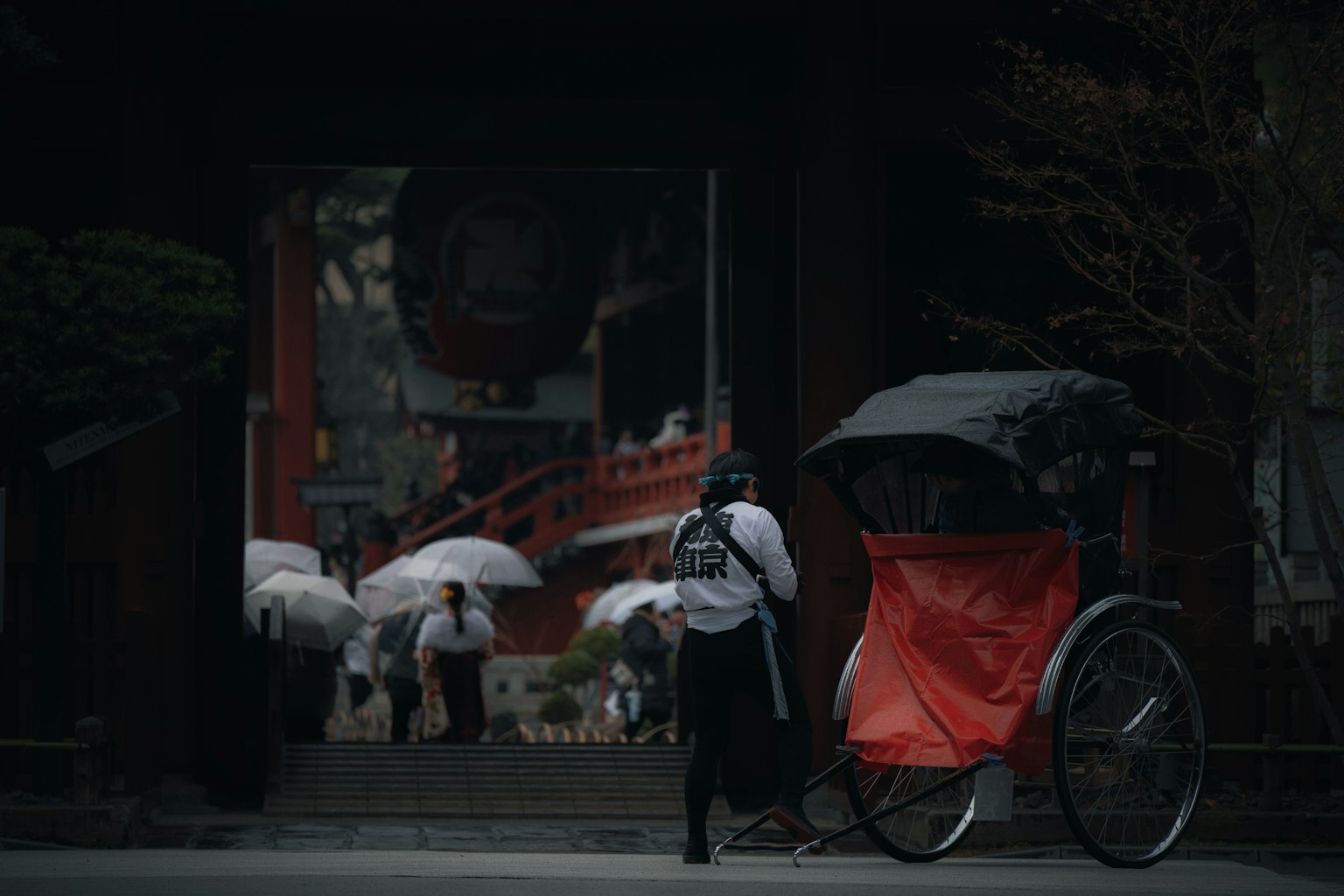 Szene eines japanischen Tempels mit einer Rikscha und Touristen mit Regenschirmen