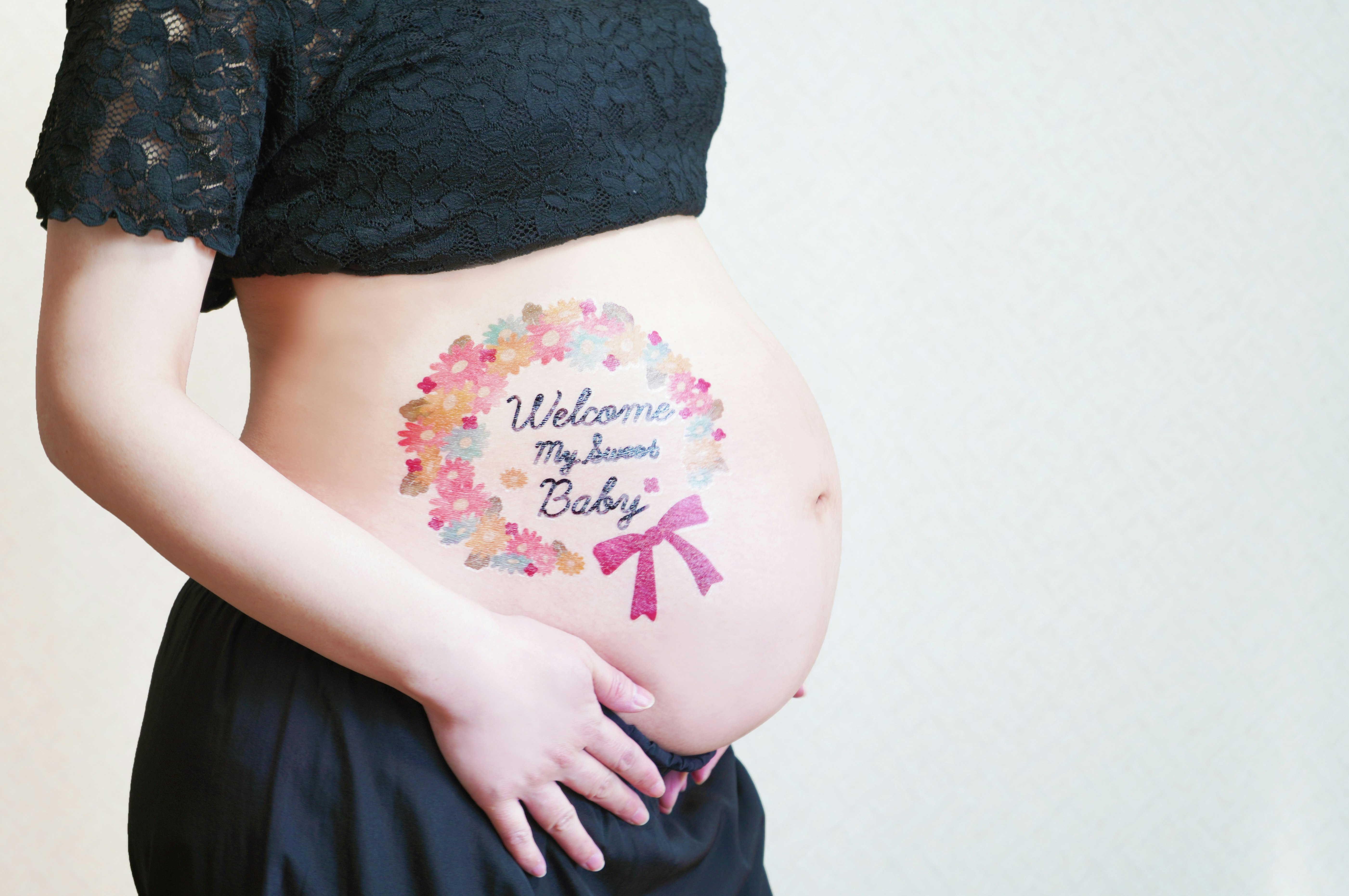 手を添えた妊婦のお腹に入ったベビーウェルカムの文字