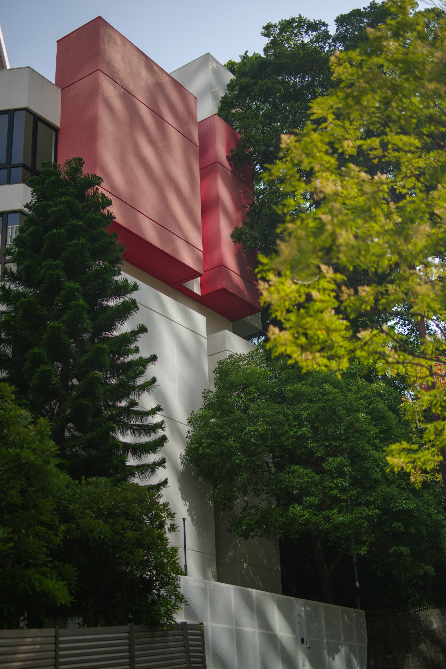 Bâtiment moderne avec des accents rouges et des arbres verts luxuriants