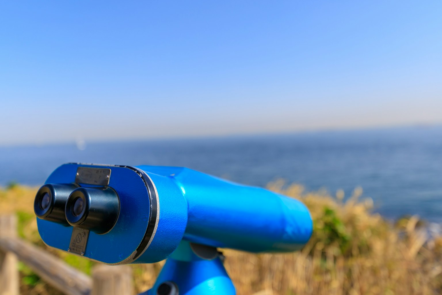 Telescopio azul que mira al océano bajo un cielo despejado