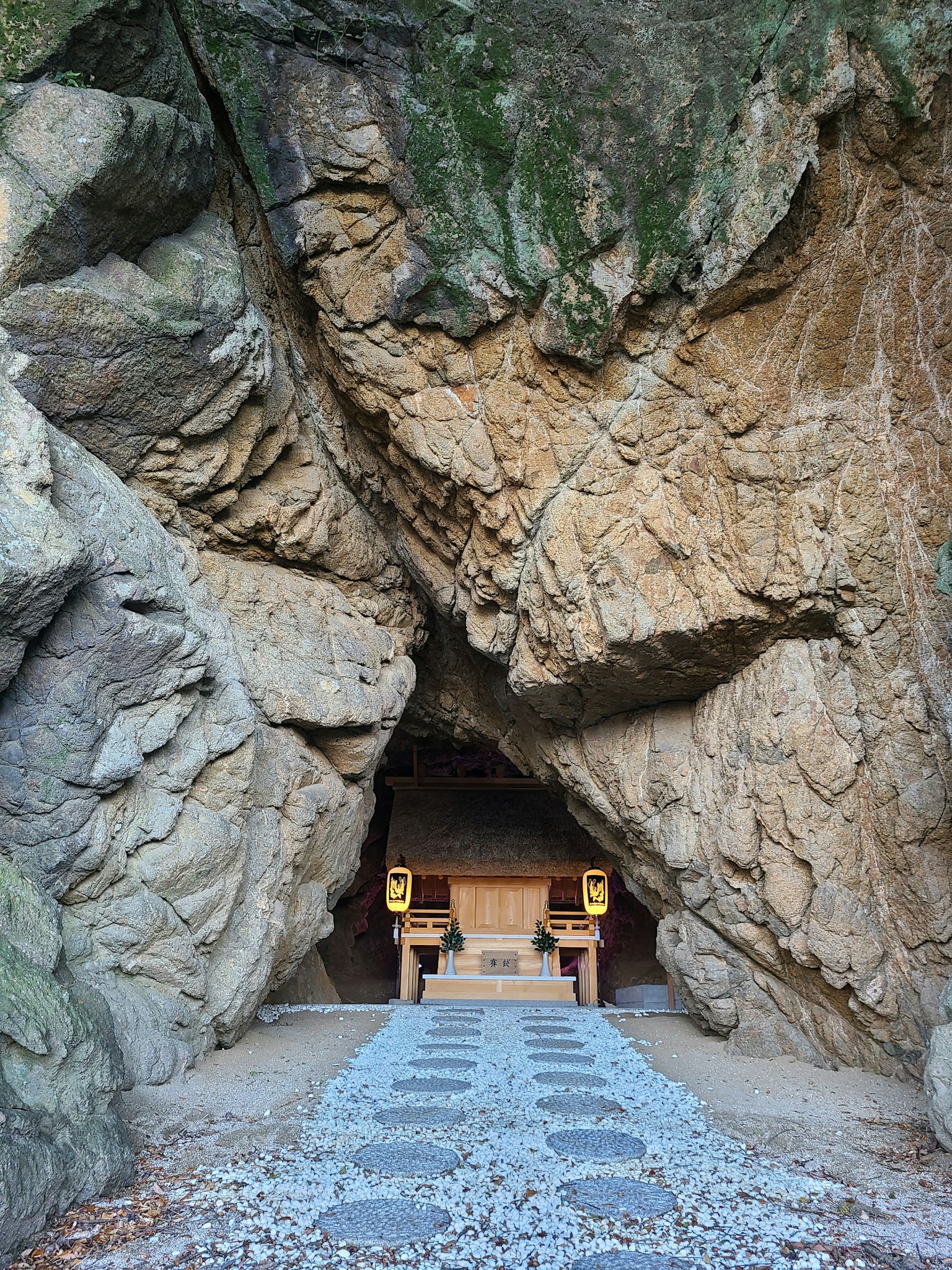 Entrance to a shrine nestled in rocks with a stone pathway