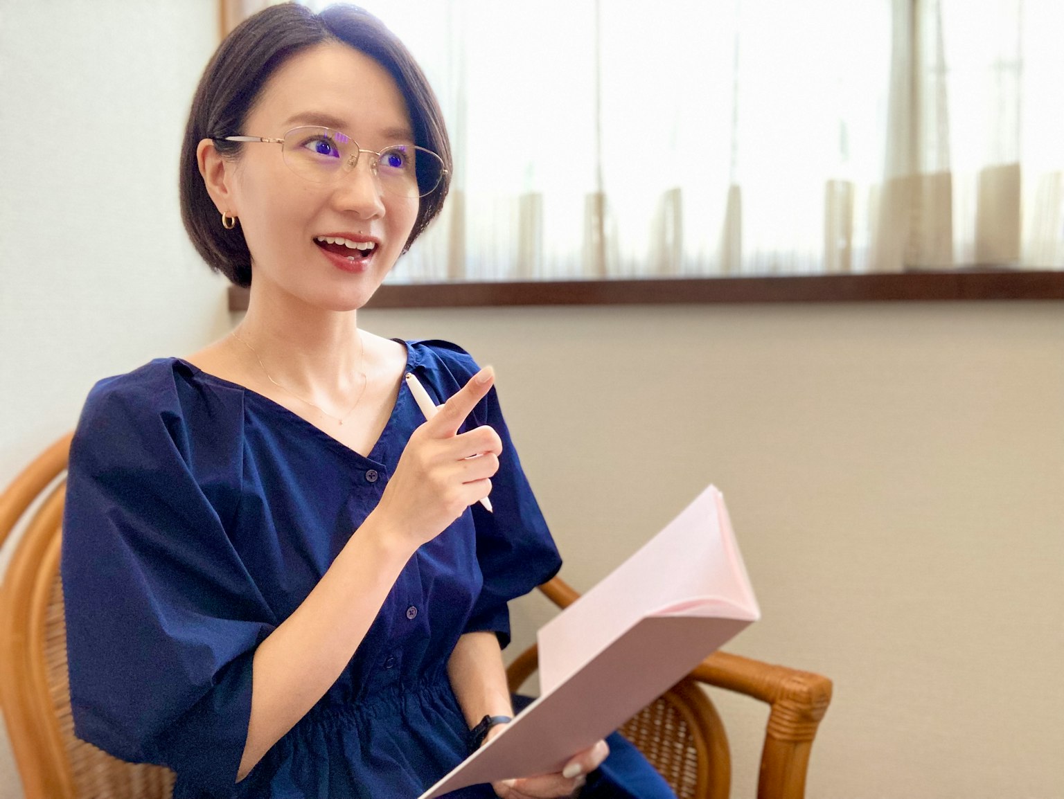 Seorang wanita berpakaian santai memegang buku catatan dan menunjuk dengan jari