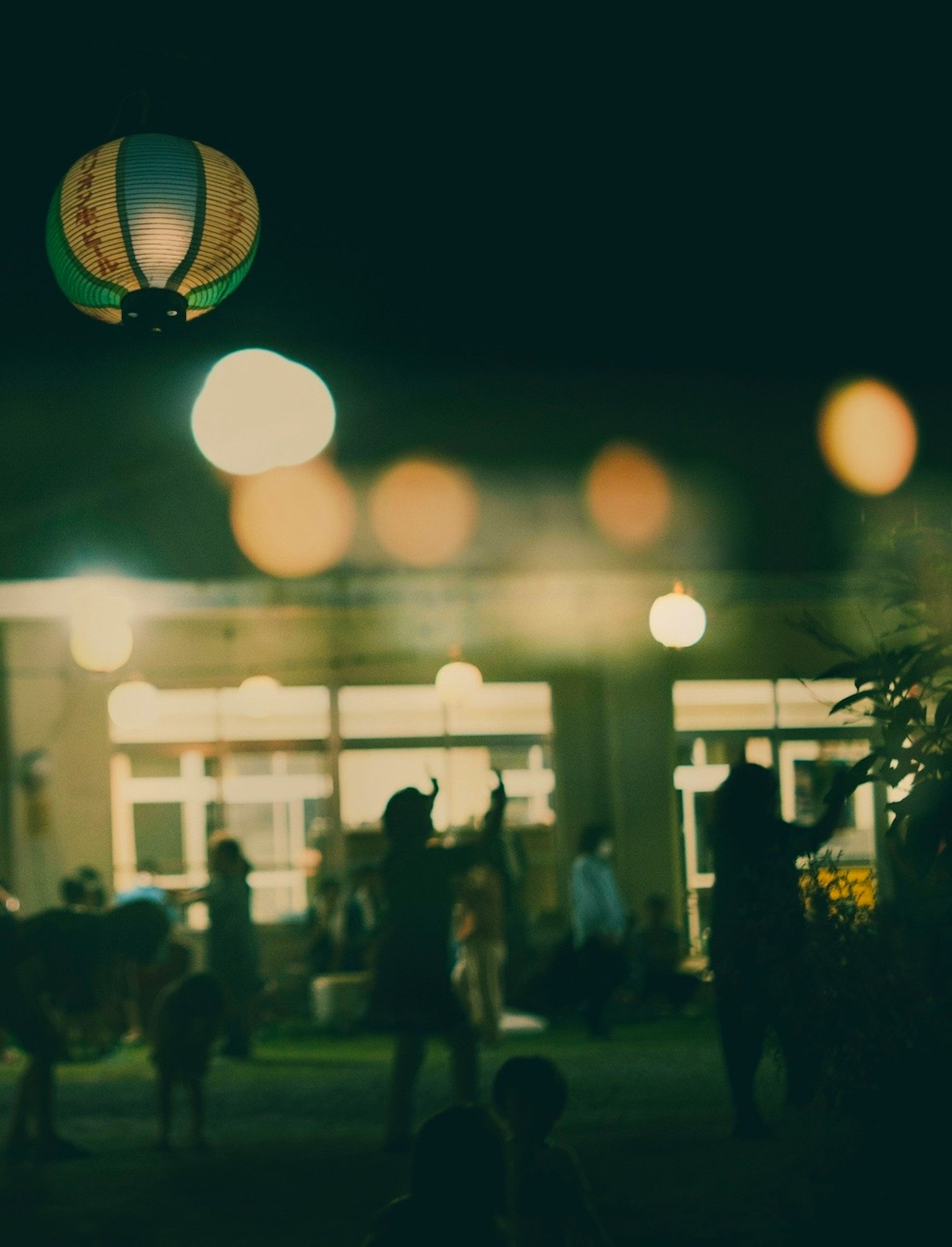 Escena de festival nocturno con luces borrosas y siluetas de personas