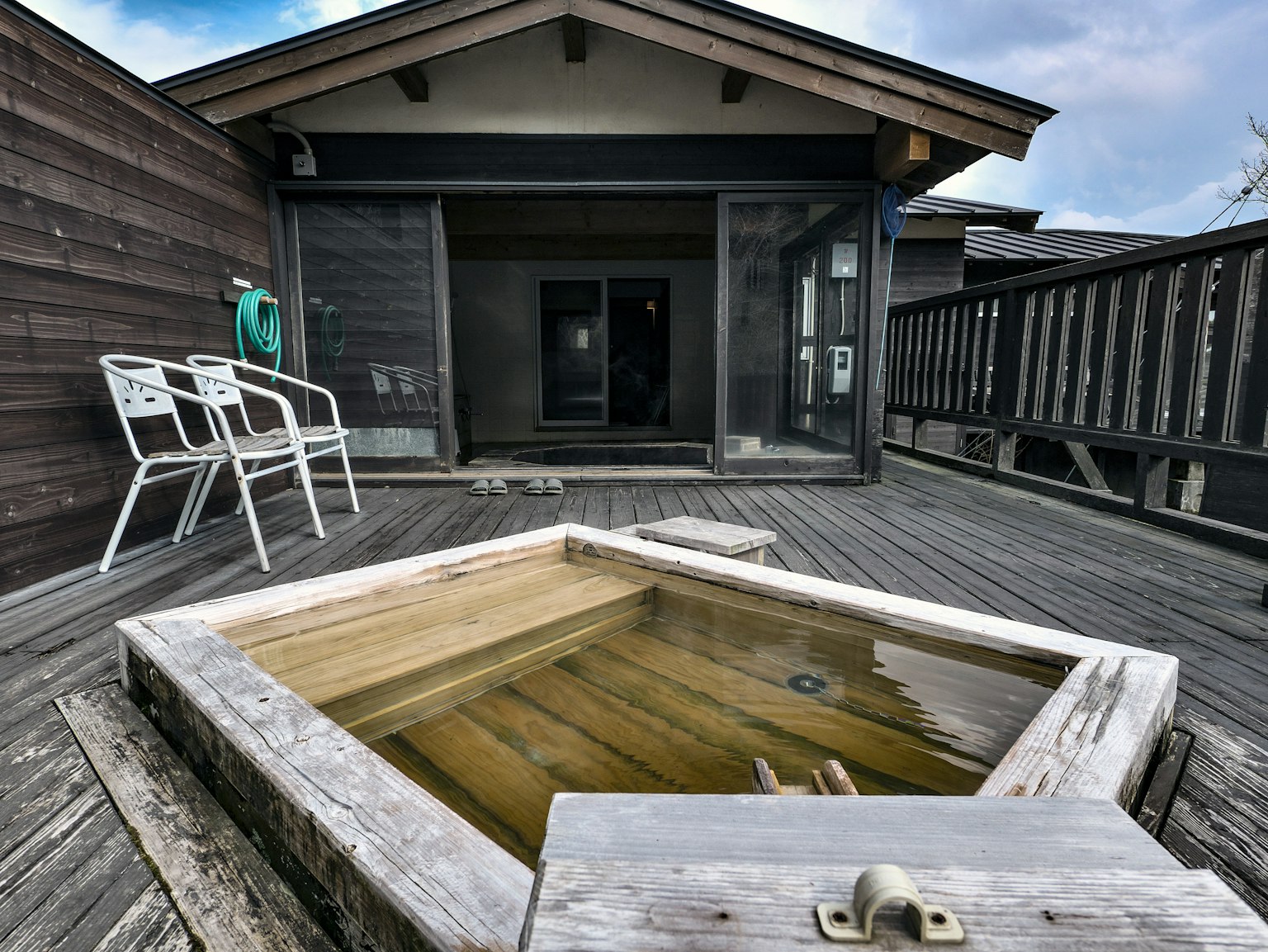 Baño exterior de madera en una terraza con sillas simples