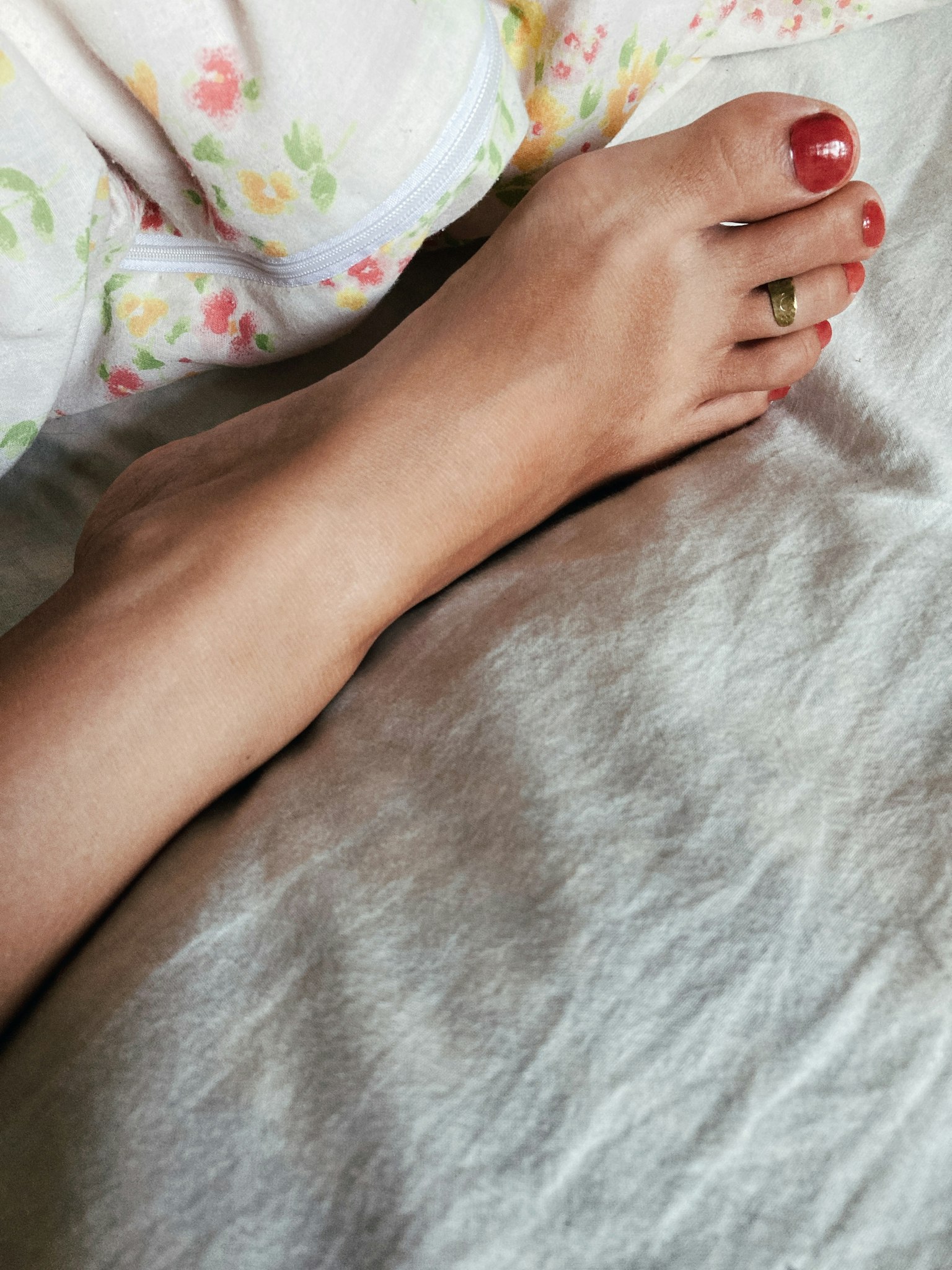Gros plan d'un pied sur un lit avec du vernis à ongles rouge