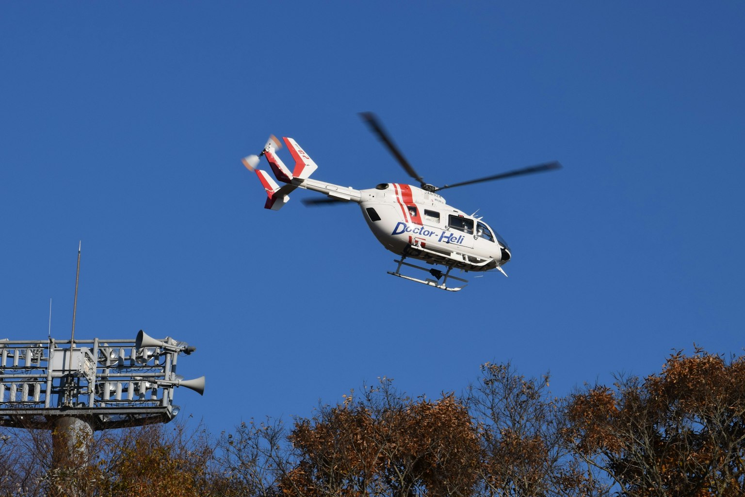 Hélicoptère blanc et rouge en vol contre un ciel bleu