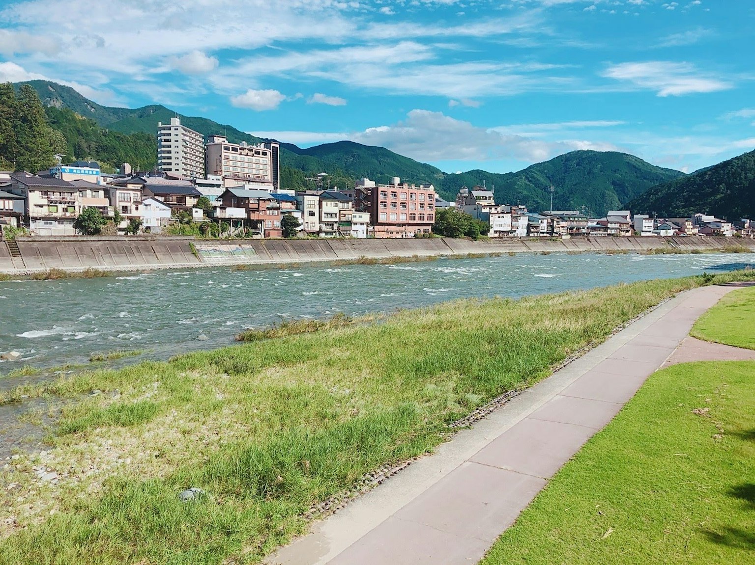 Scenic view of a river surrounded by mountains and buildings under a clear blue sky