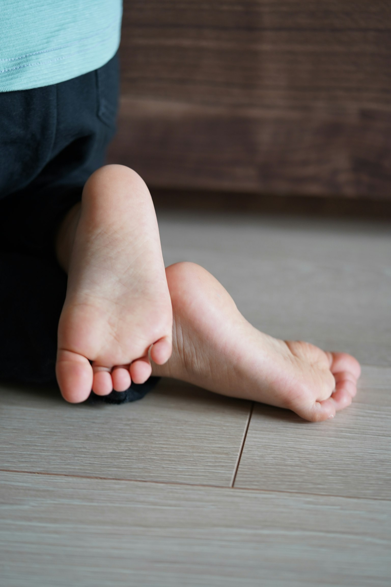Bàn chân trần của trẻ em resting trên sàn gỗ