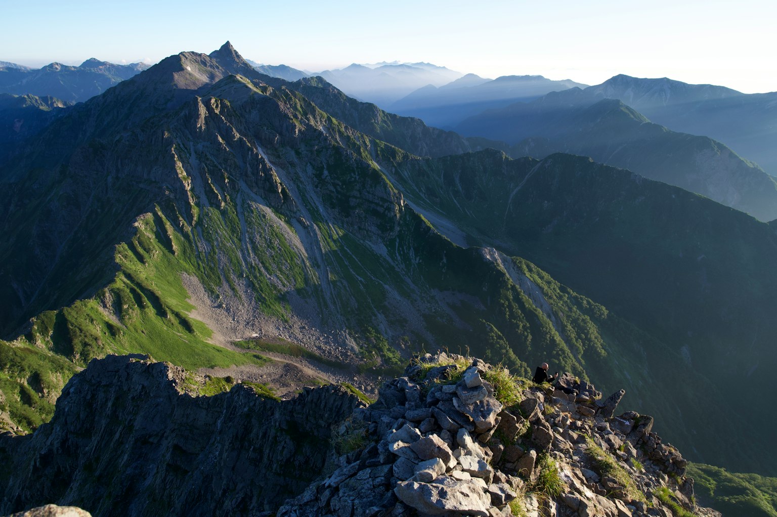 Stunning view from the mountain peak featuring green mountains and a blue sky