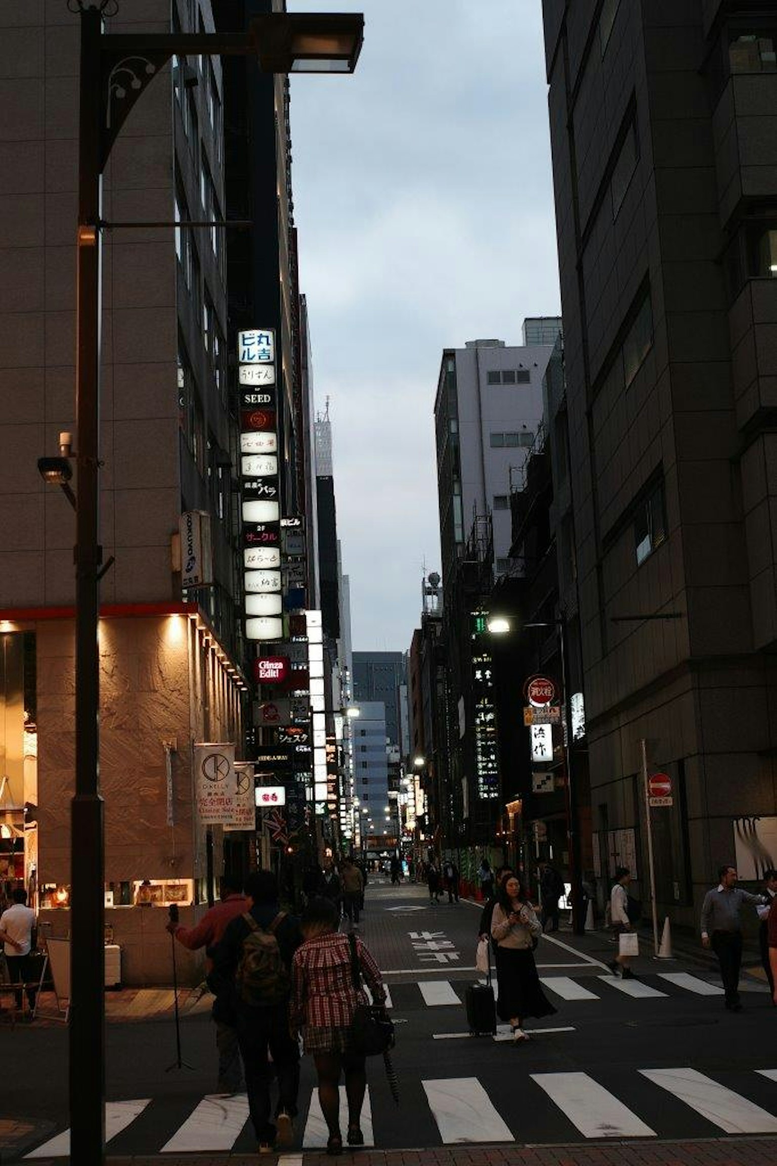 People walking on a city street during twilight