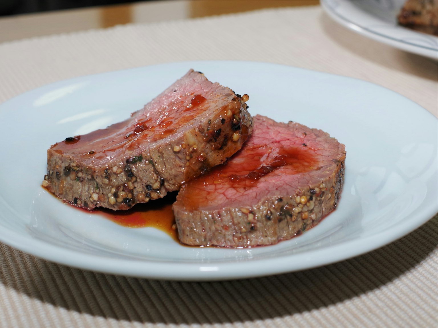 Sliced roast beef on a white plate with a pink center