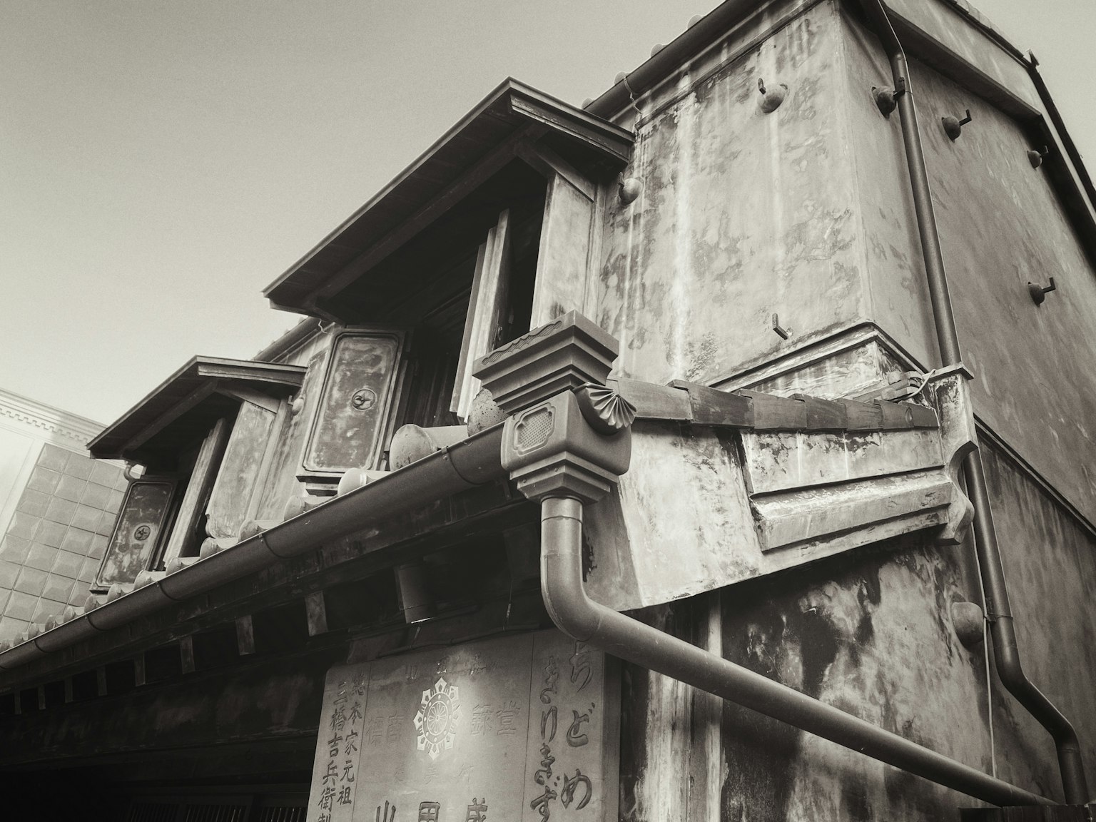 Black and white photograph showcasing details of an old building roof and windows