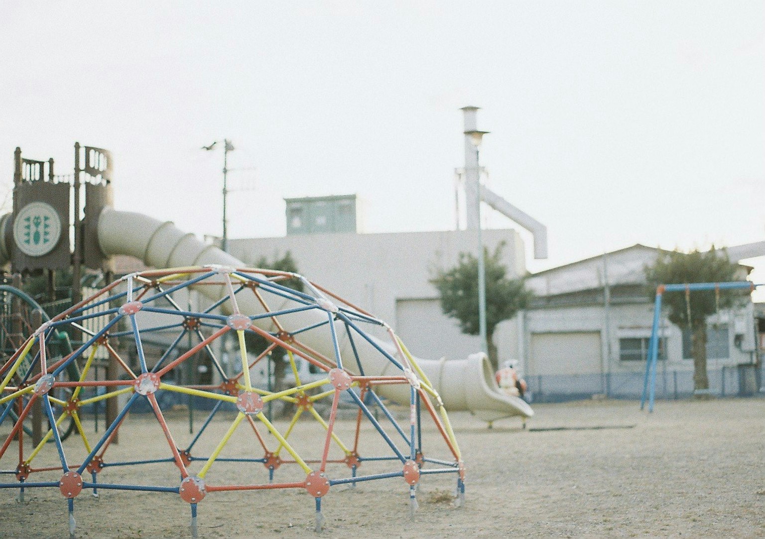 Scena di un parco con una struttura di arrampicata colorata e uno scivolo