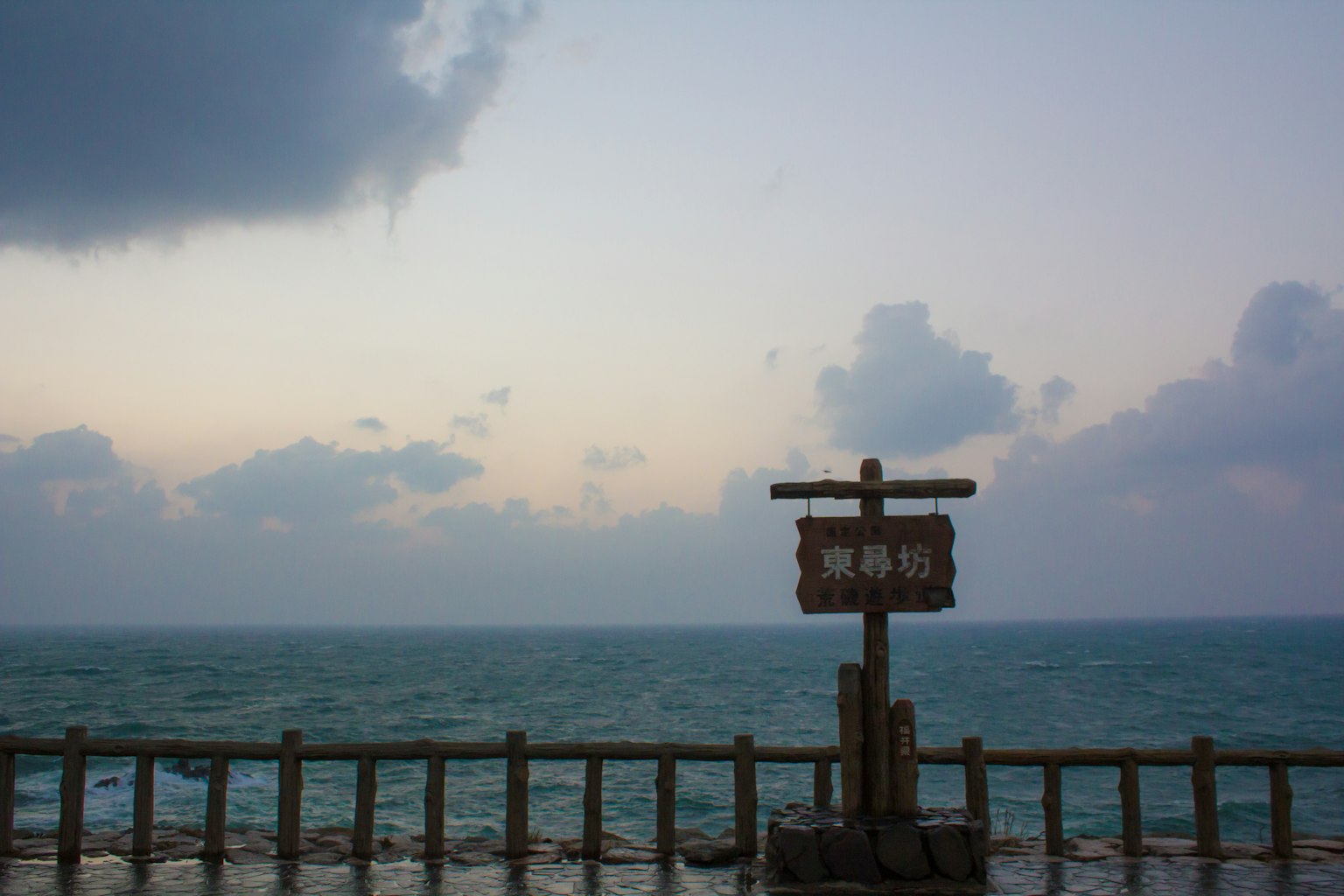 Holzschild mit Blick auf ein weites Meer und den Himmel