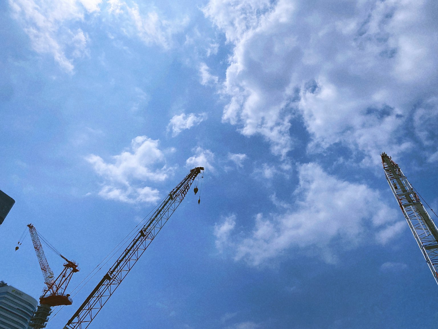 Cranes at a construction site under a blue sky