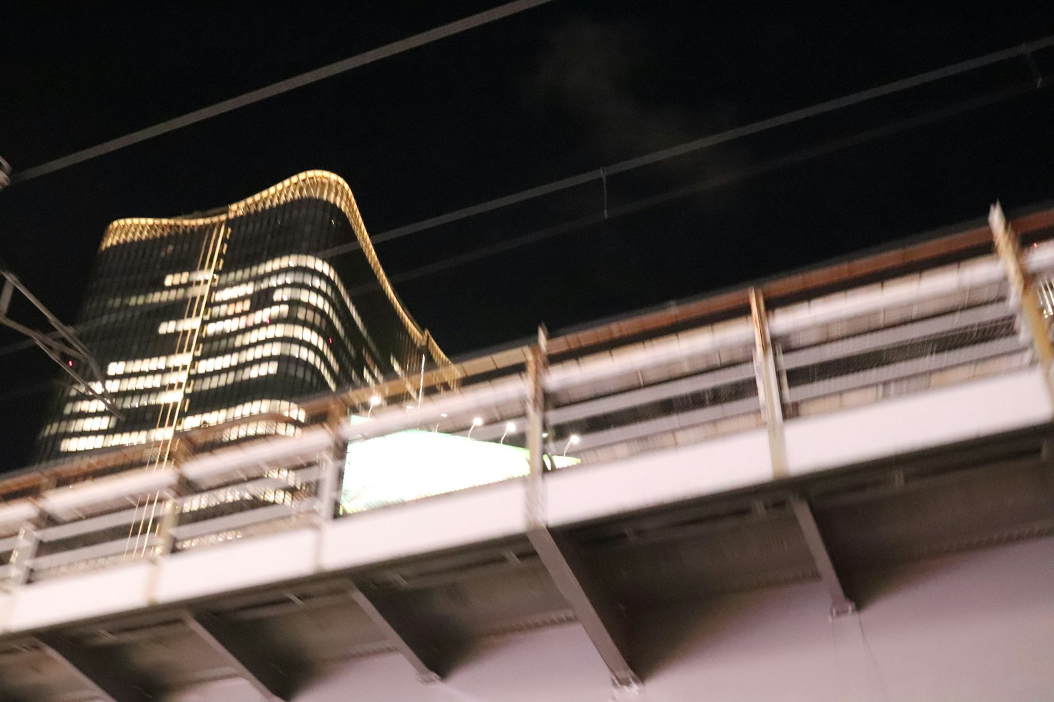 Grattacielo illuminato contro il cielo notturno con struttura ferroviaria
