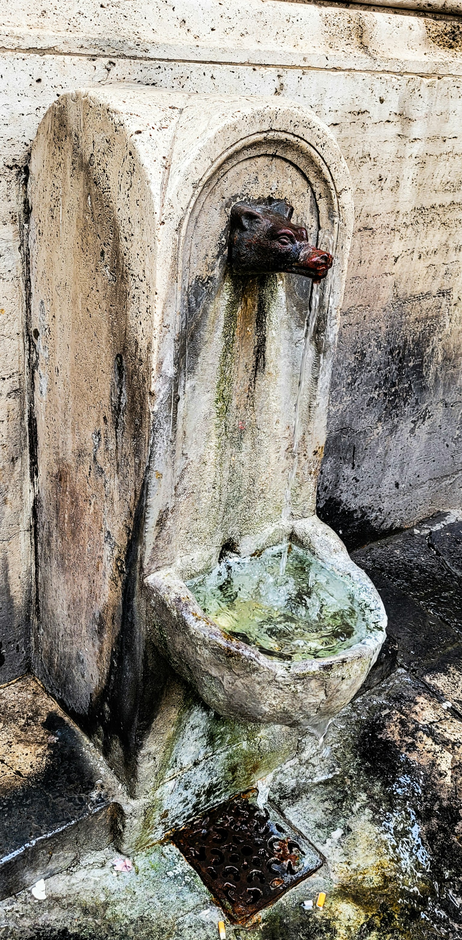 古老的石製噴泉固定在牆上，水流出