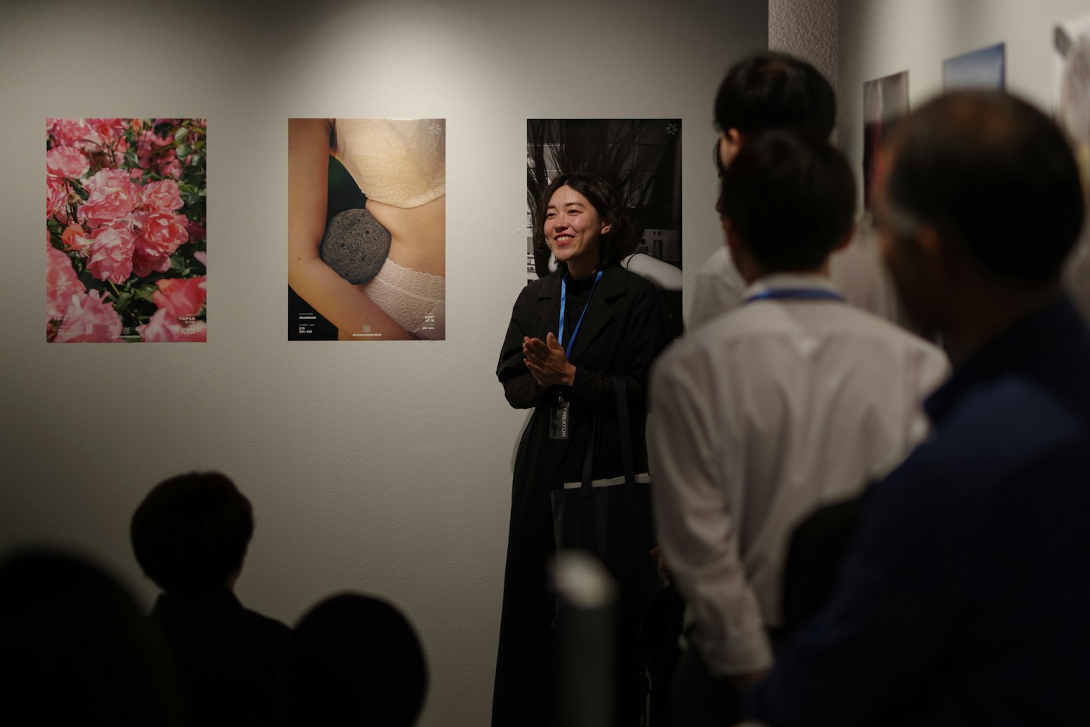 展示会で話す女性と写真が飾られた壁