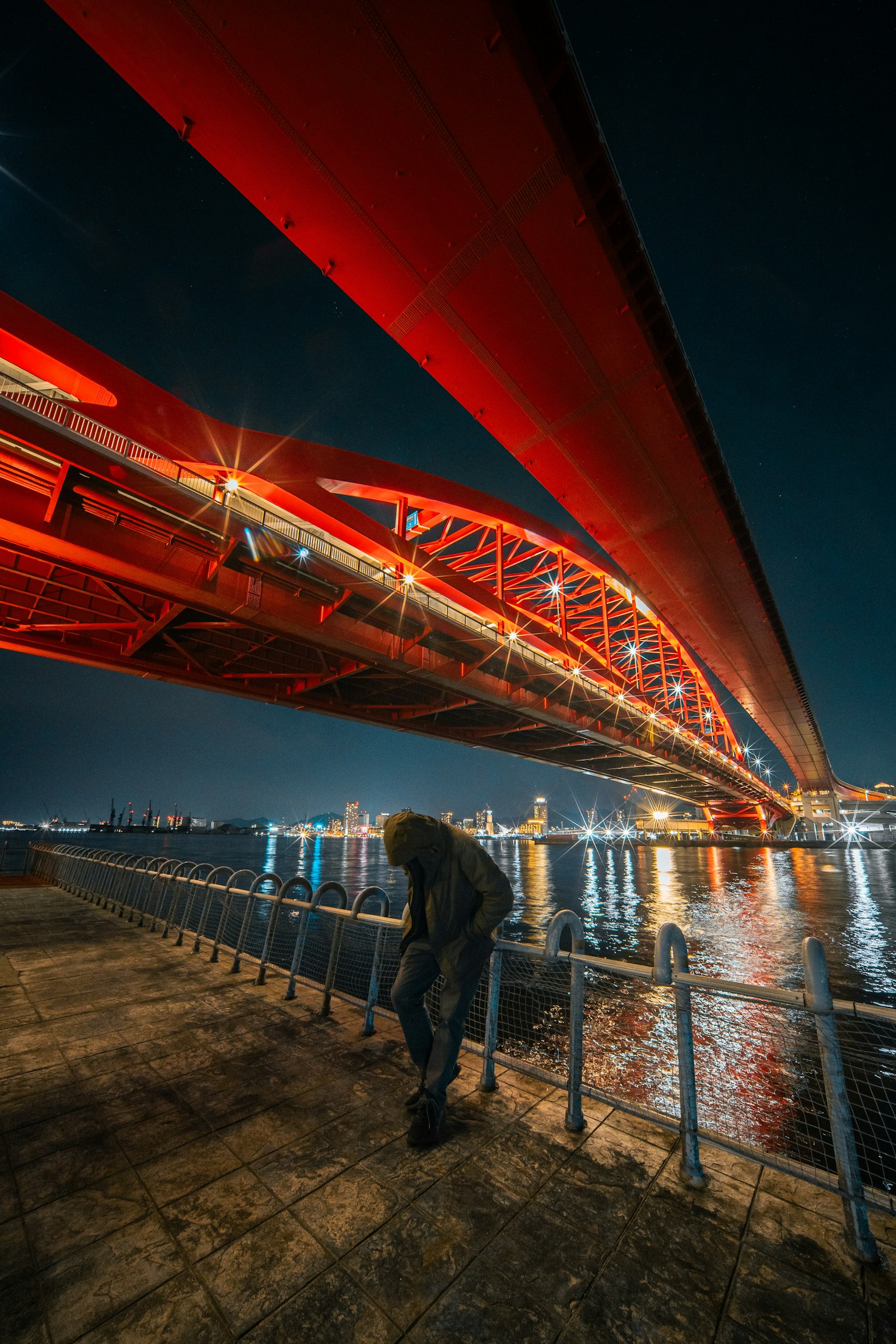 Ponte rosso illuminato di notte con riflessi sull'acqua
