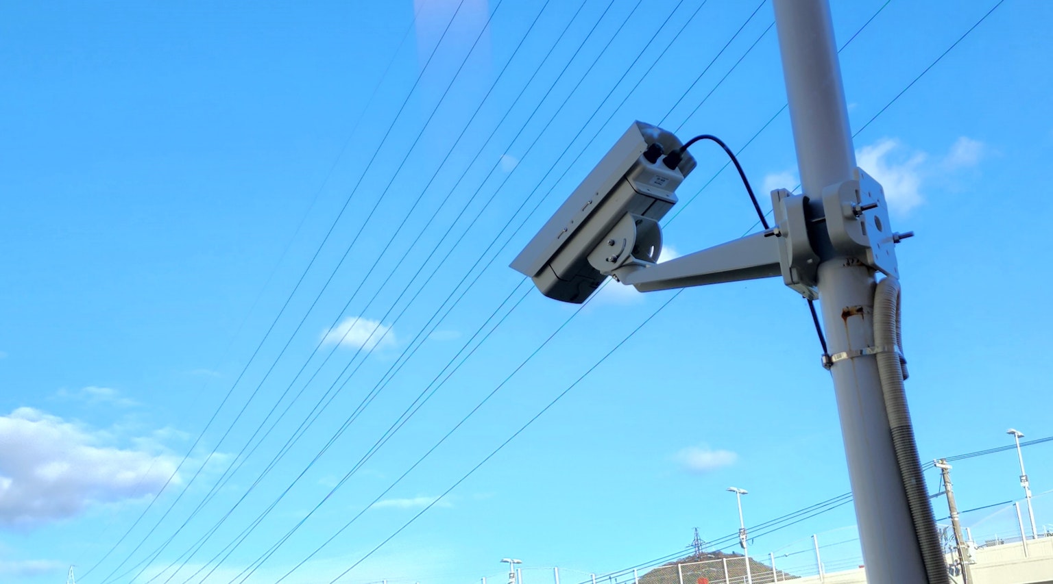 Surveillance camera mounted on a pole under a blue sky