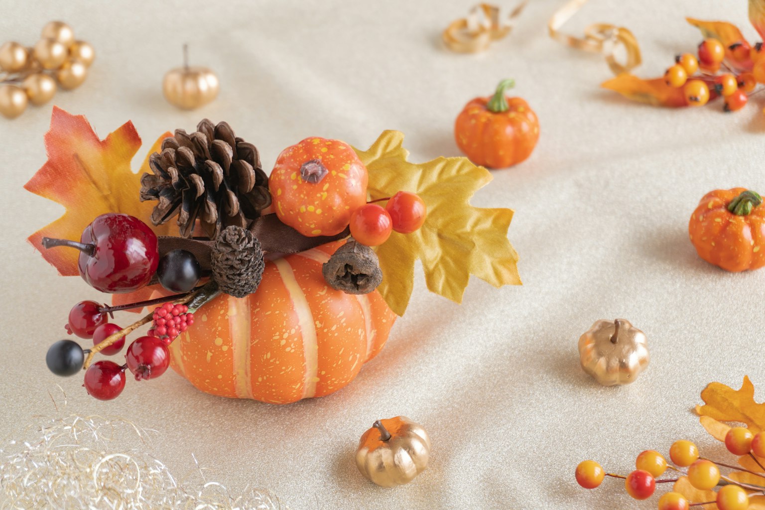 Herbstdekoration mit einem kleinen Kürbis- und Kiefernzapfenarrangement
