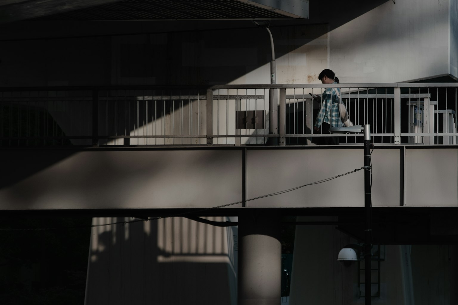 Una persona seduta su un ponte con ombre che creano motivi interessanti