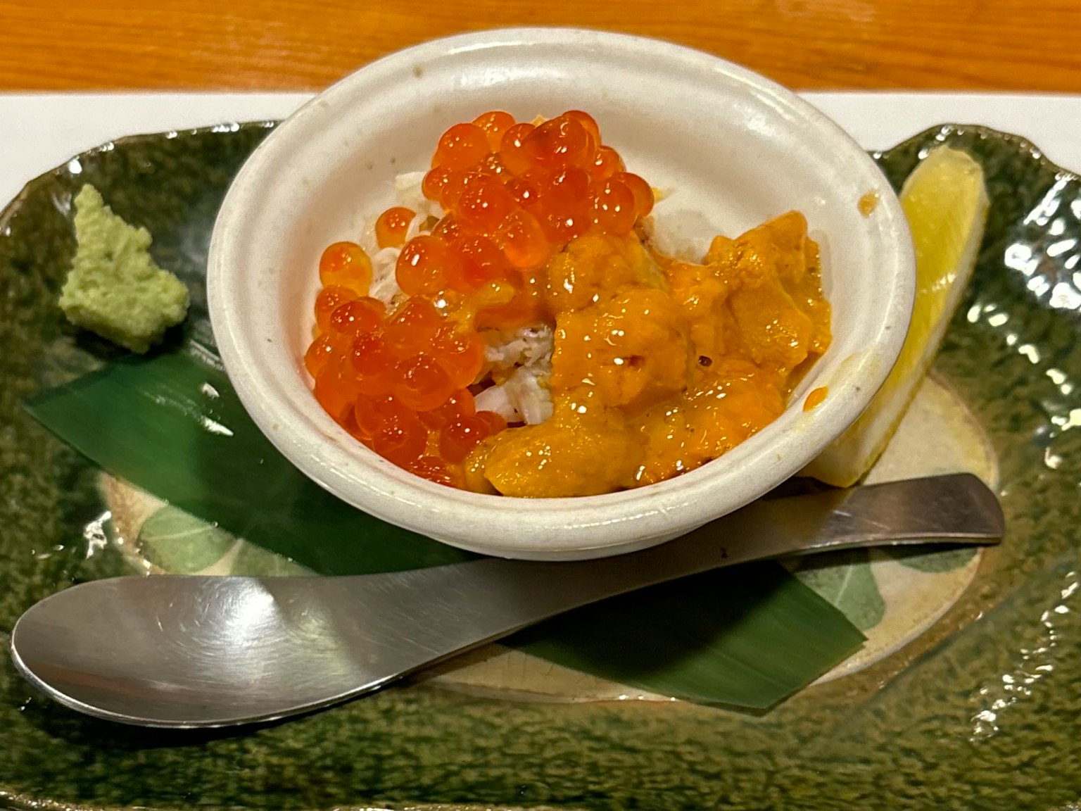 Piring kecil dengan uni krim dan telur salmon cerah, disajikan dengan wasabi dan lemon