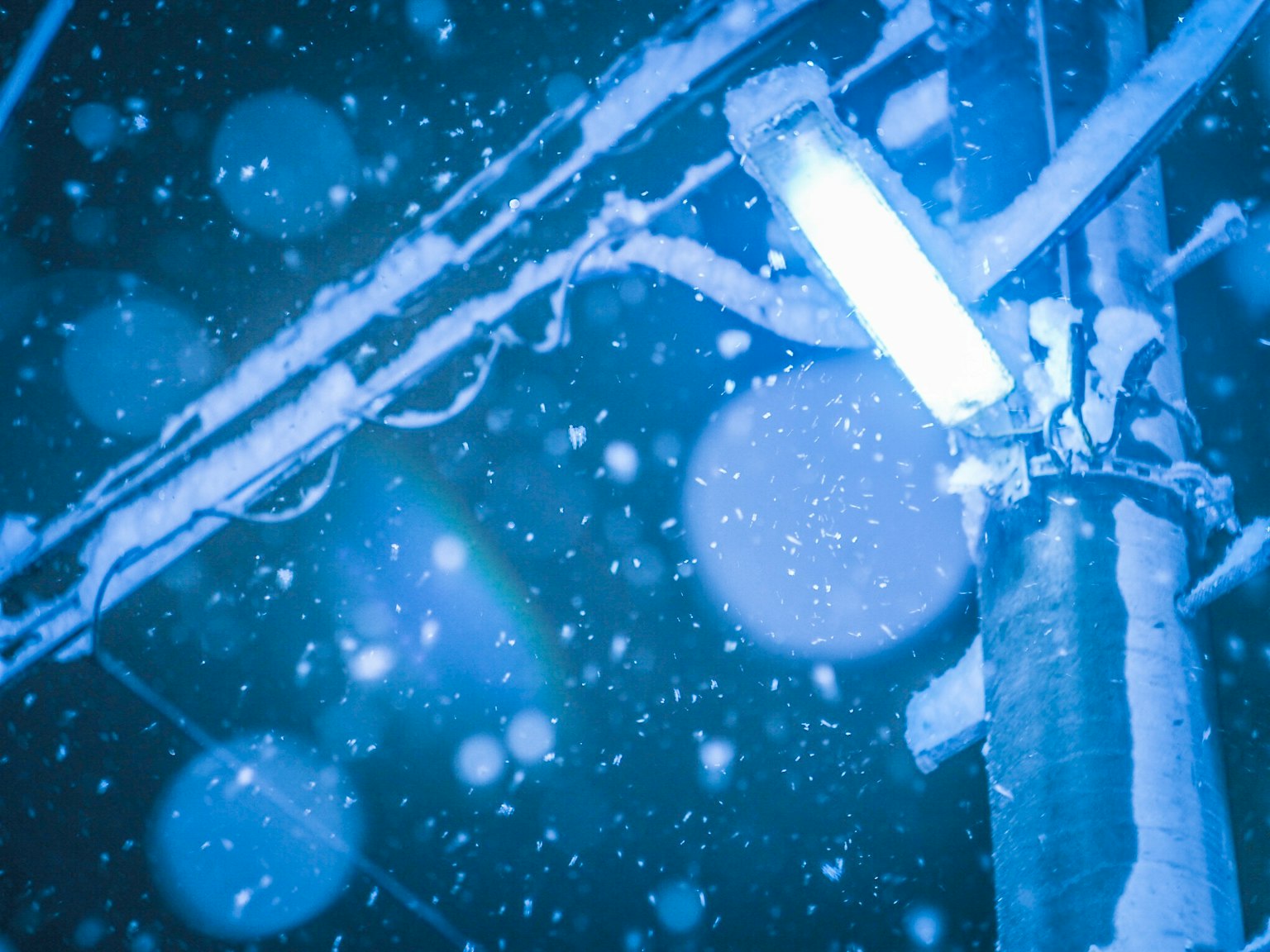 Close-up of a blue streetlight and utility pole in the snow