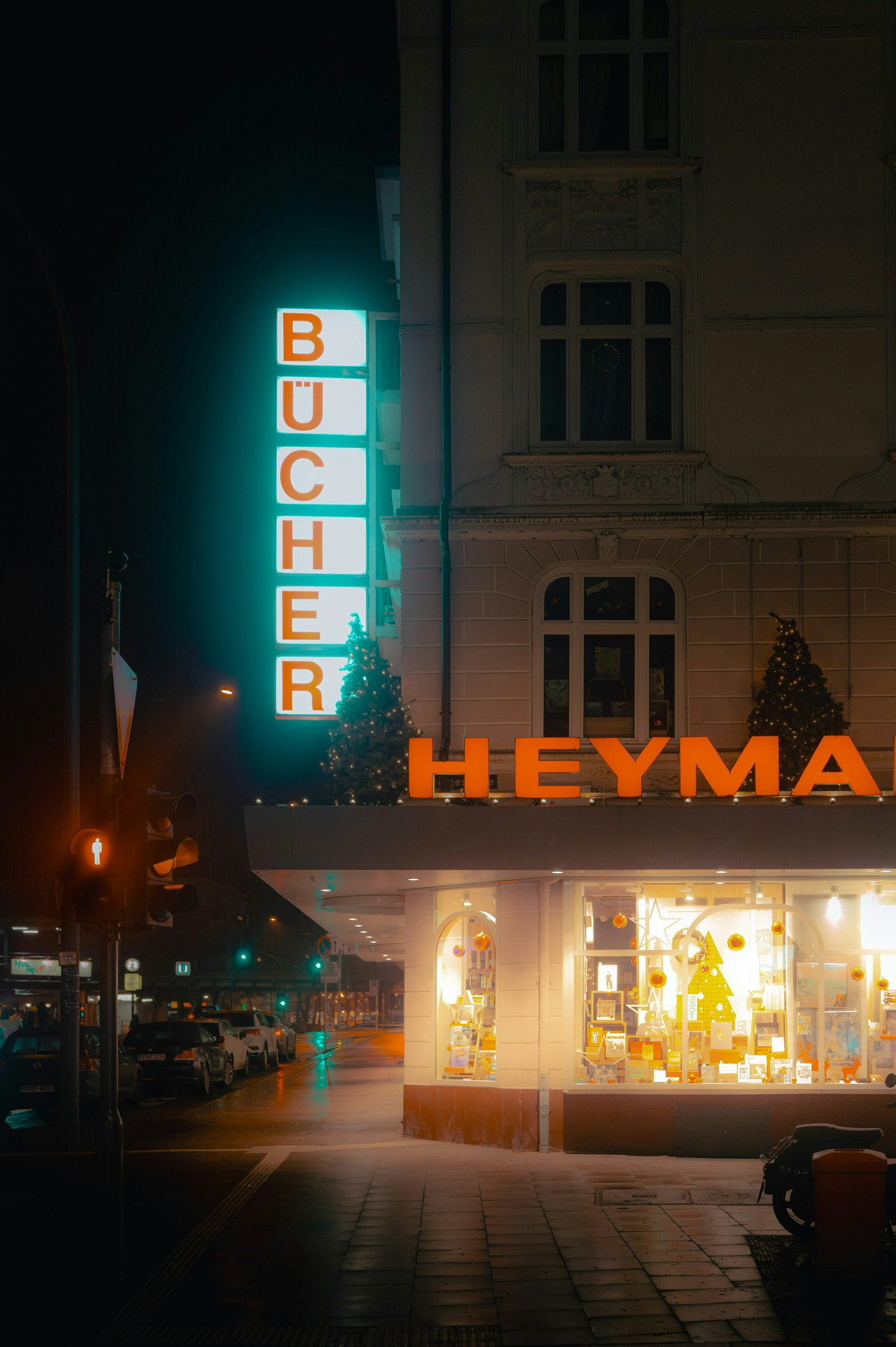 夜の街角にあるブッヘルの看板とヘイマの店舗が明るく照らされている