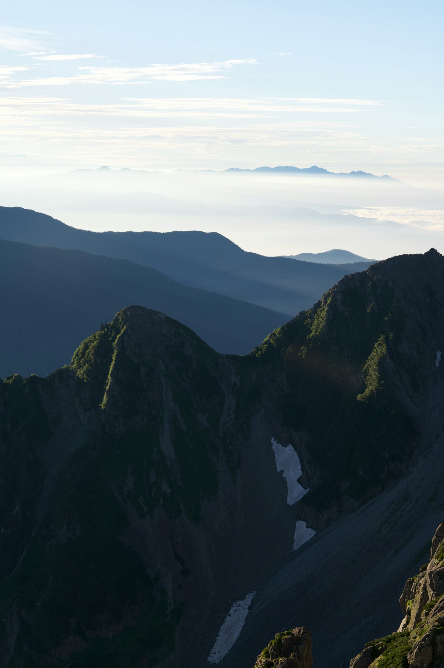 Silhouettes of mountains with a sea of clouds in the background and a blue sky