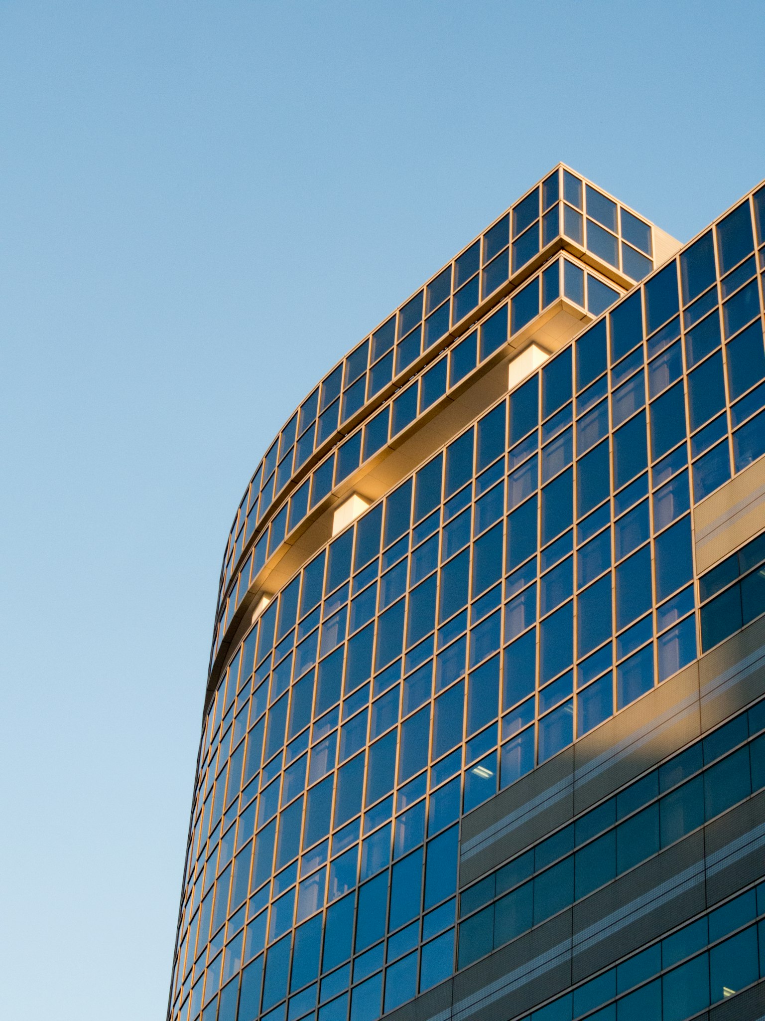 Modern skyscraper viewed from an angle showcasing glass facade and blue sky