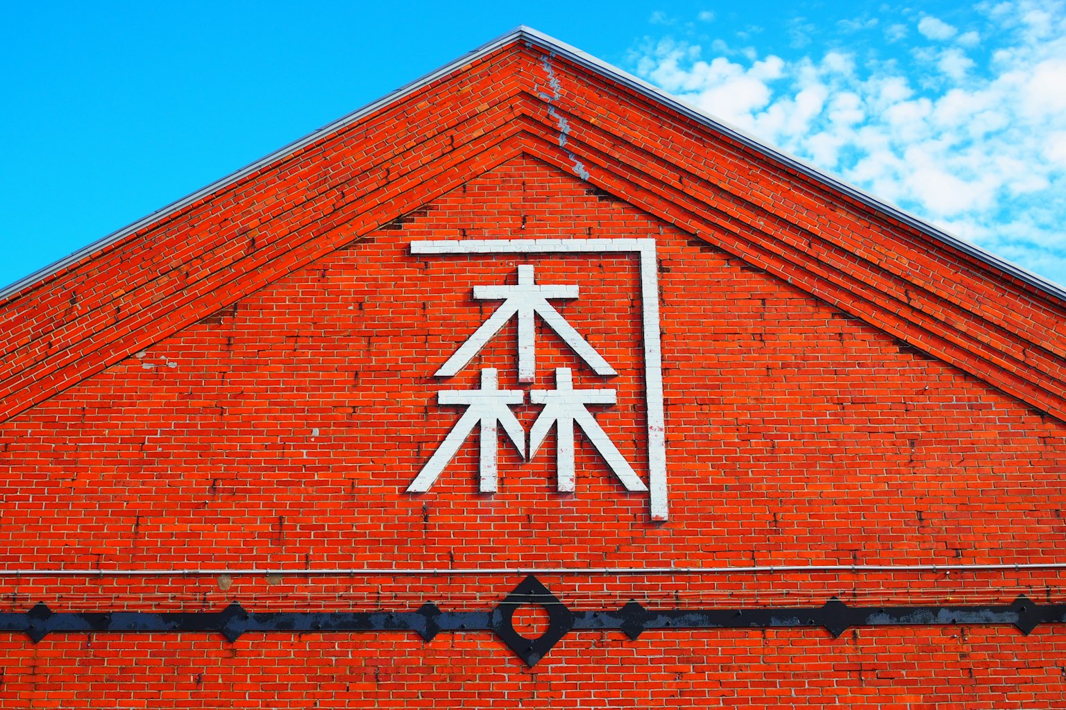 Pared de ladrillos rojos con carácter kanji blanco para 'bosque'