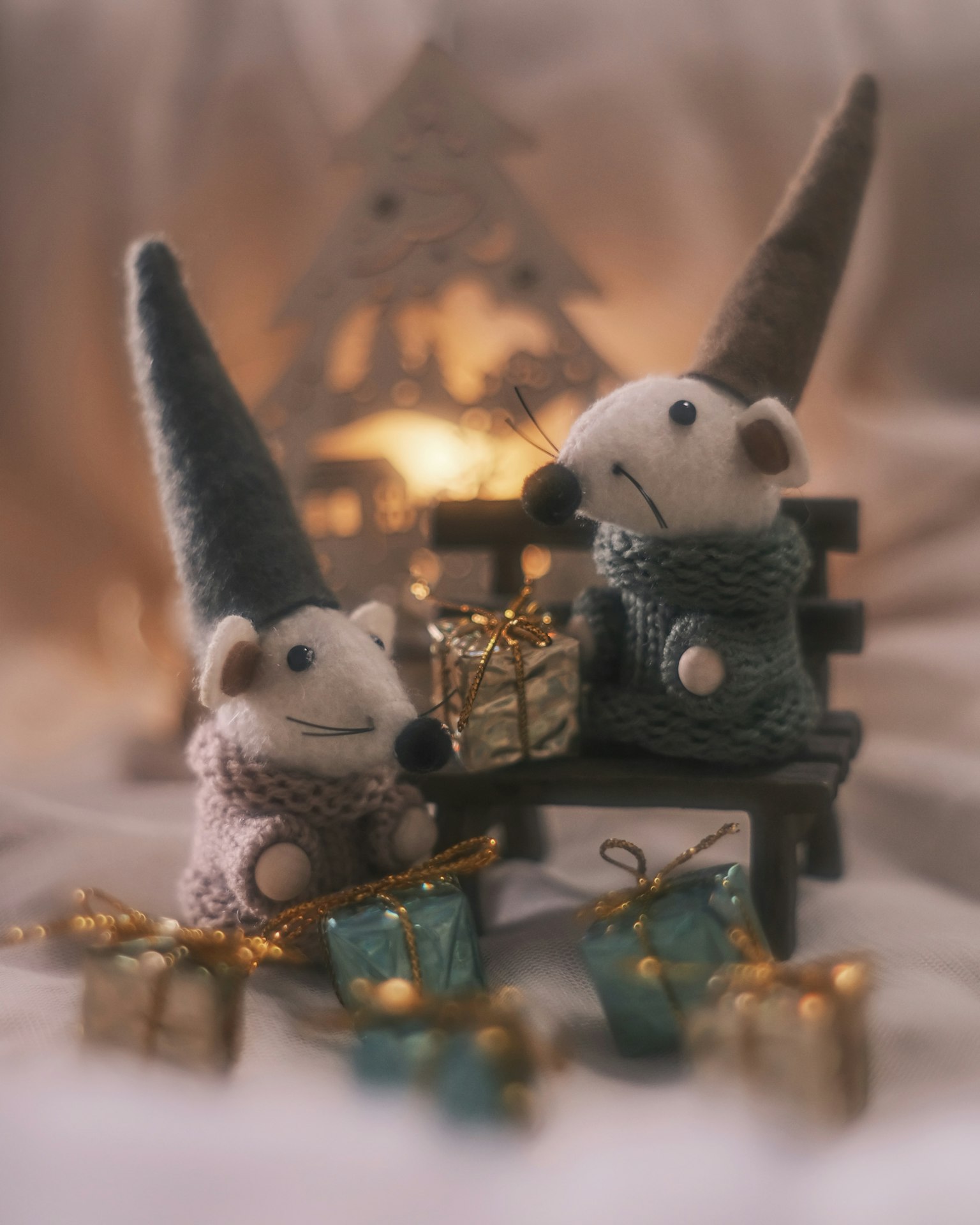 Deux petits animaux en chapeaux de Noël assis à côté d'un cadeau sur un banc en bois
