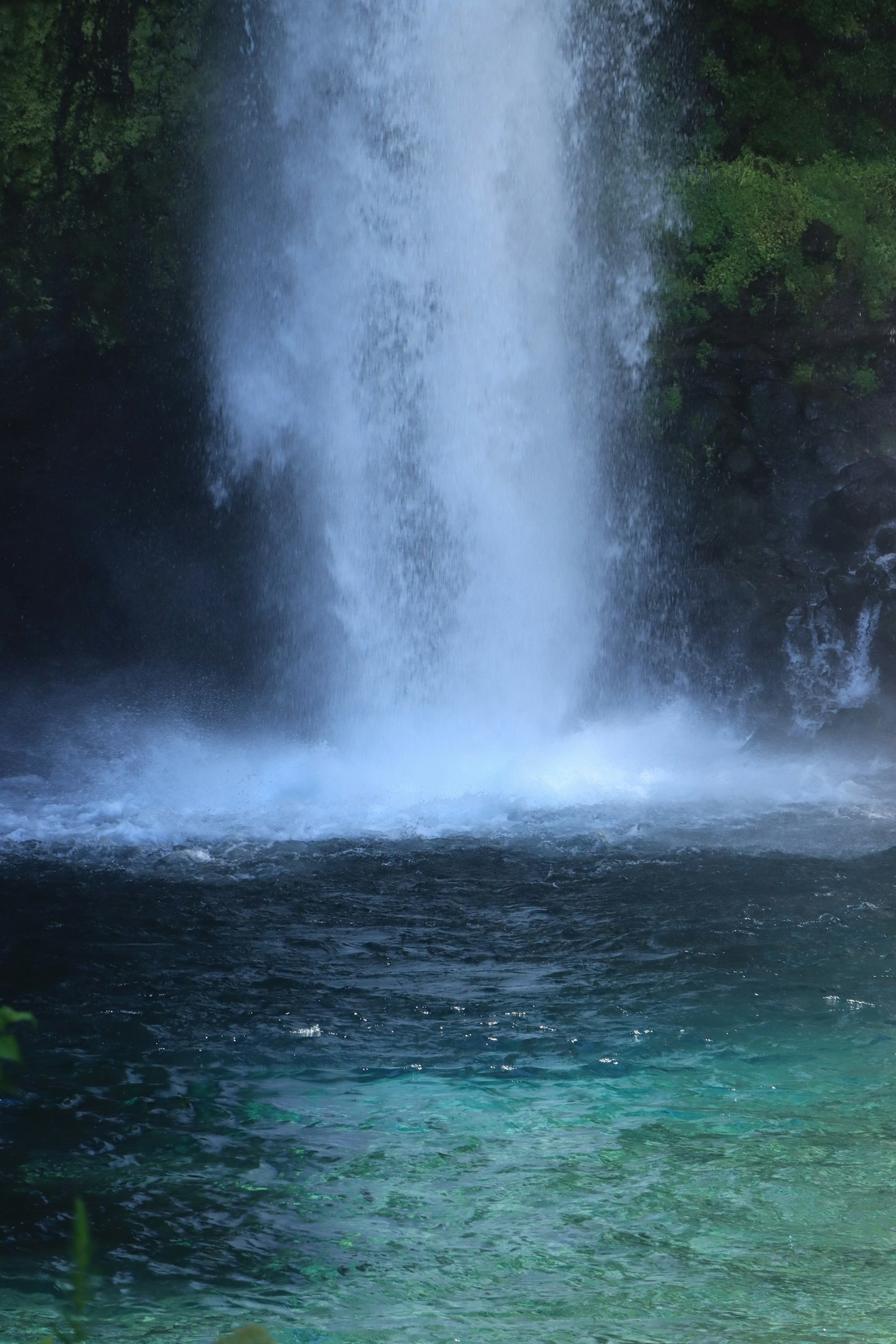 Air terjun yang indah mengalir ke kolam turquoise jernih dikelilingi oleh pepohonan hijau