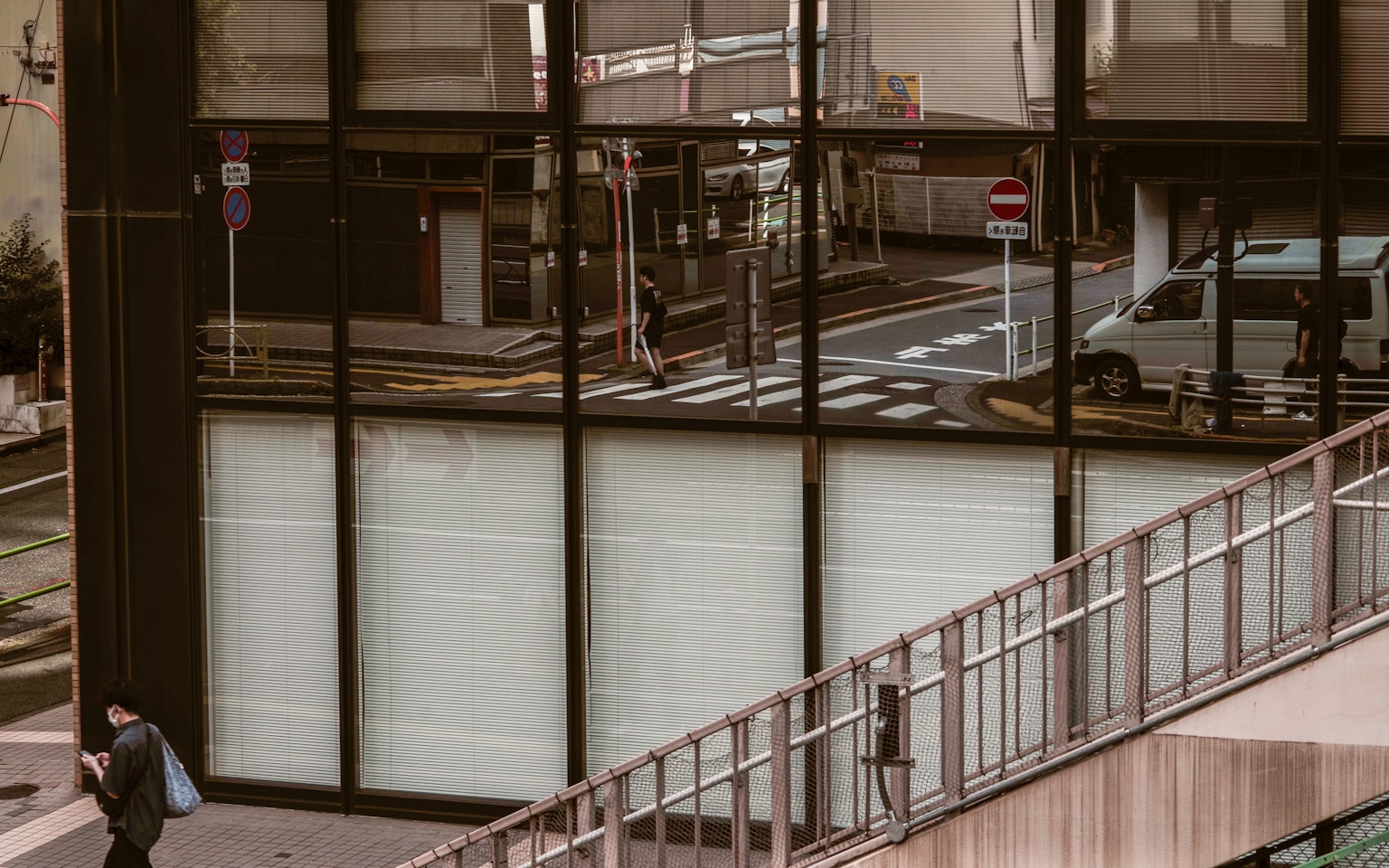 Urban scene reflected in glass with a pedestrian and street signs