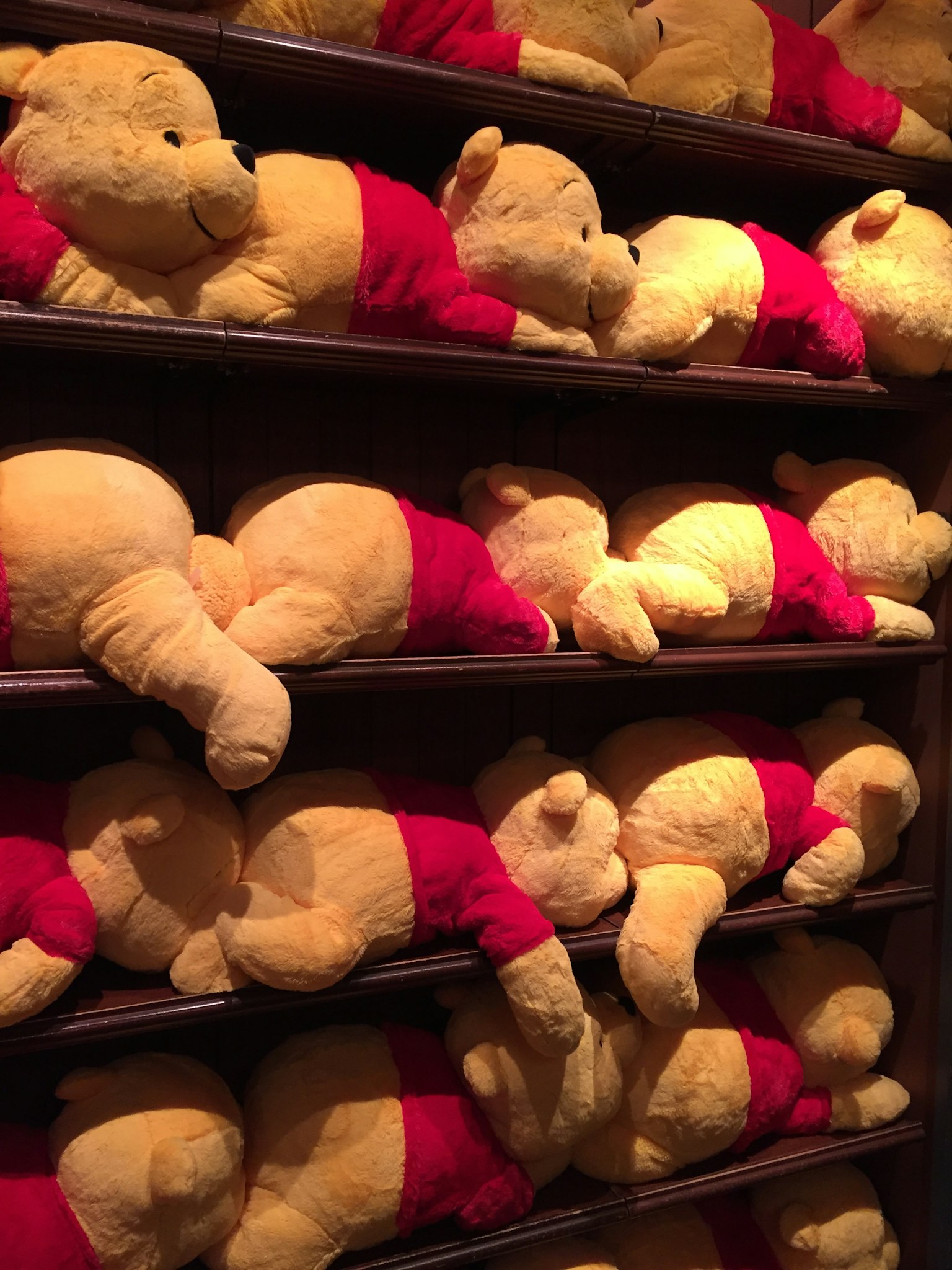 Eine Reihe von Winnie-Pooh-Plüschtieren, die auf Regalen liegen