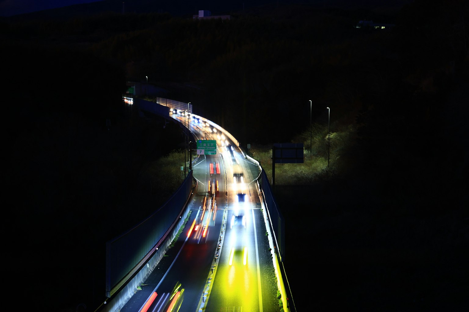 Traînées lumineuses de voitures sur une autoroute sinueuse la nuit