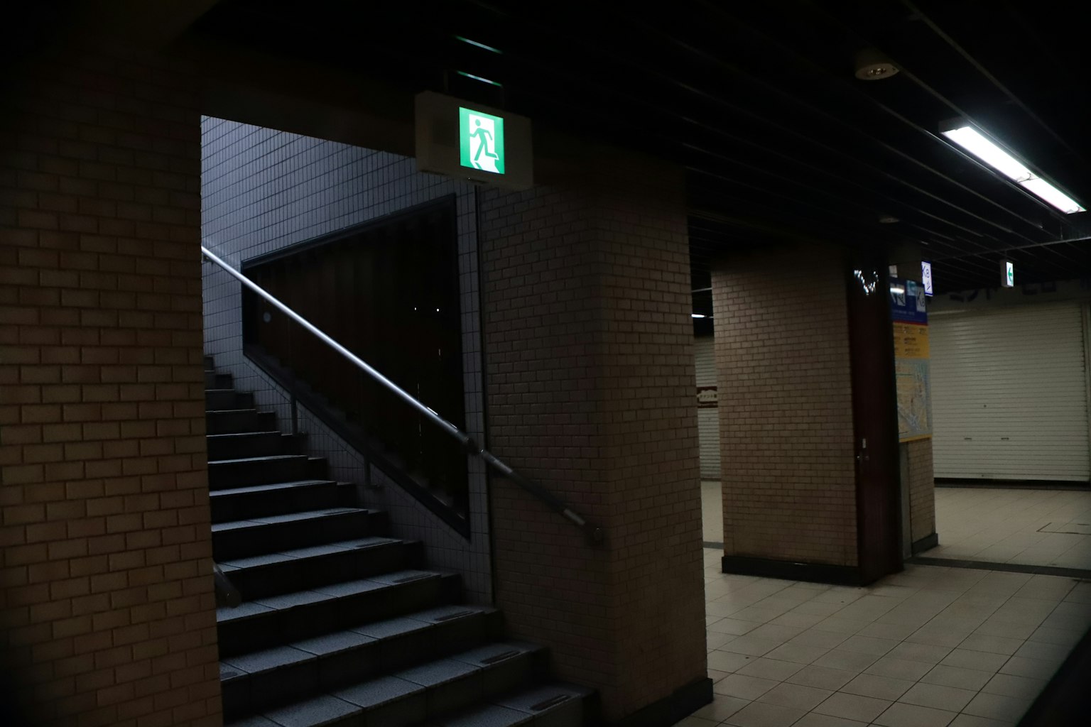 Scène de métro avec des escaliers et un panneau de sortie de secours